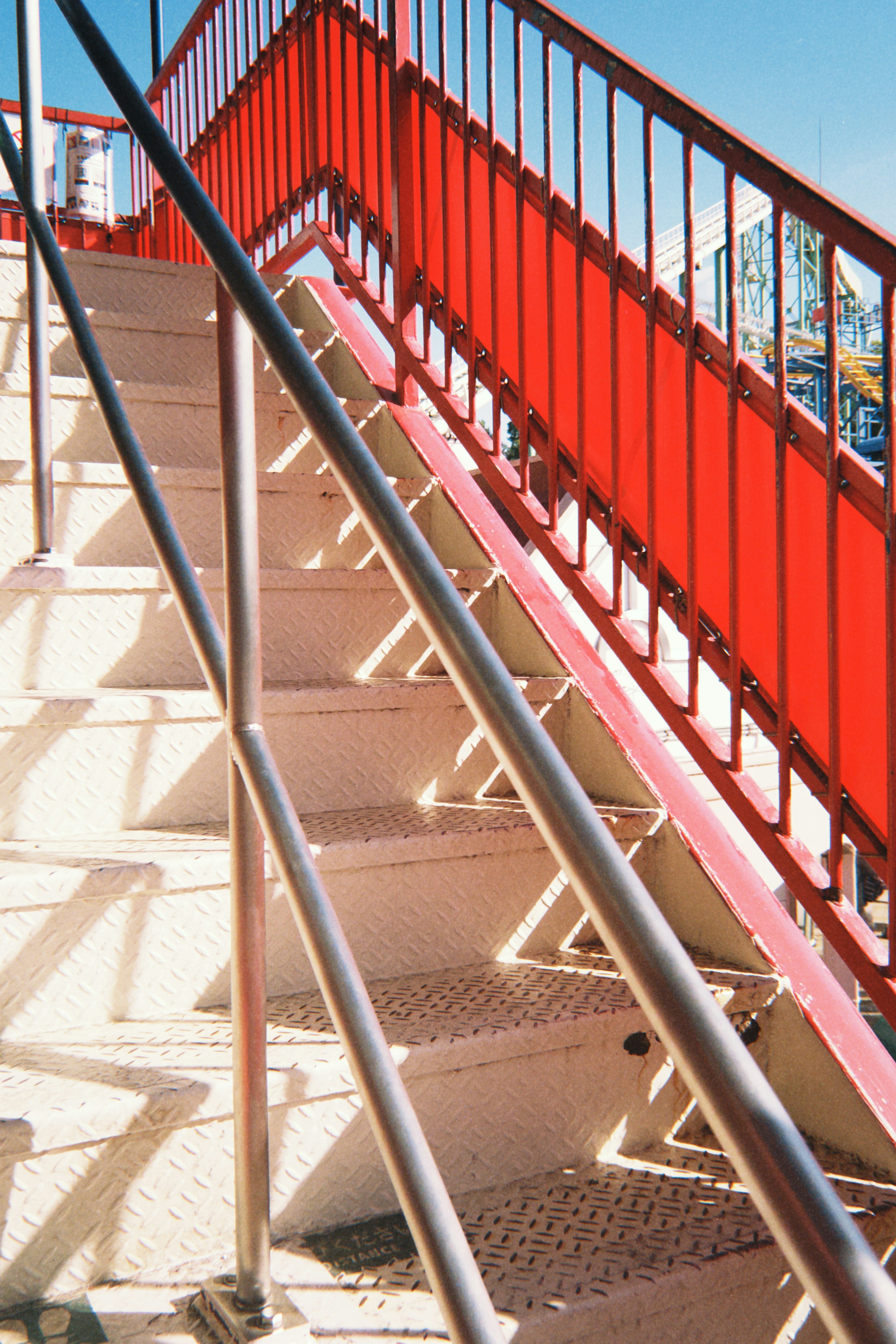 Outdoor stairs with a red railing and sunlight reflections