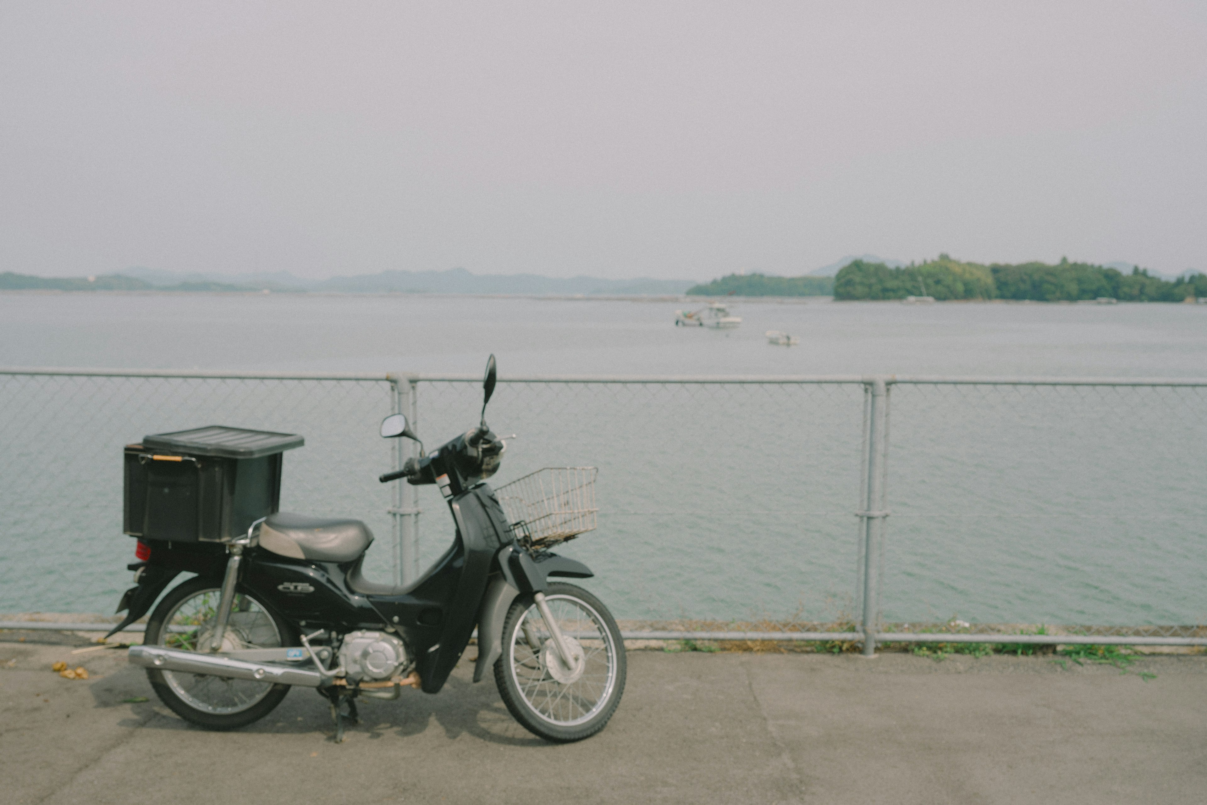 Black motorcycle parked near a lake with visible water surface