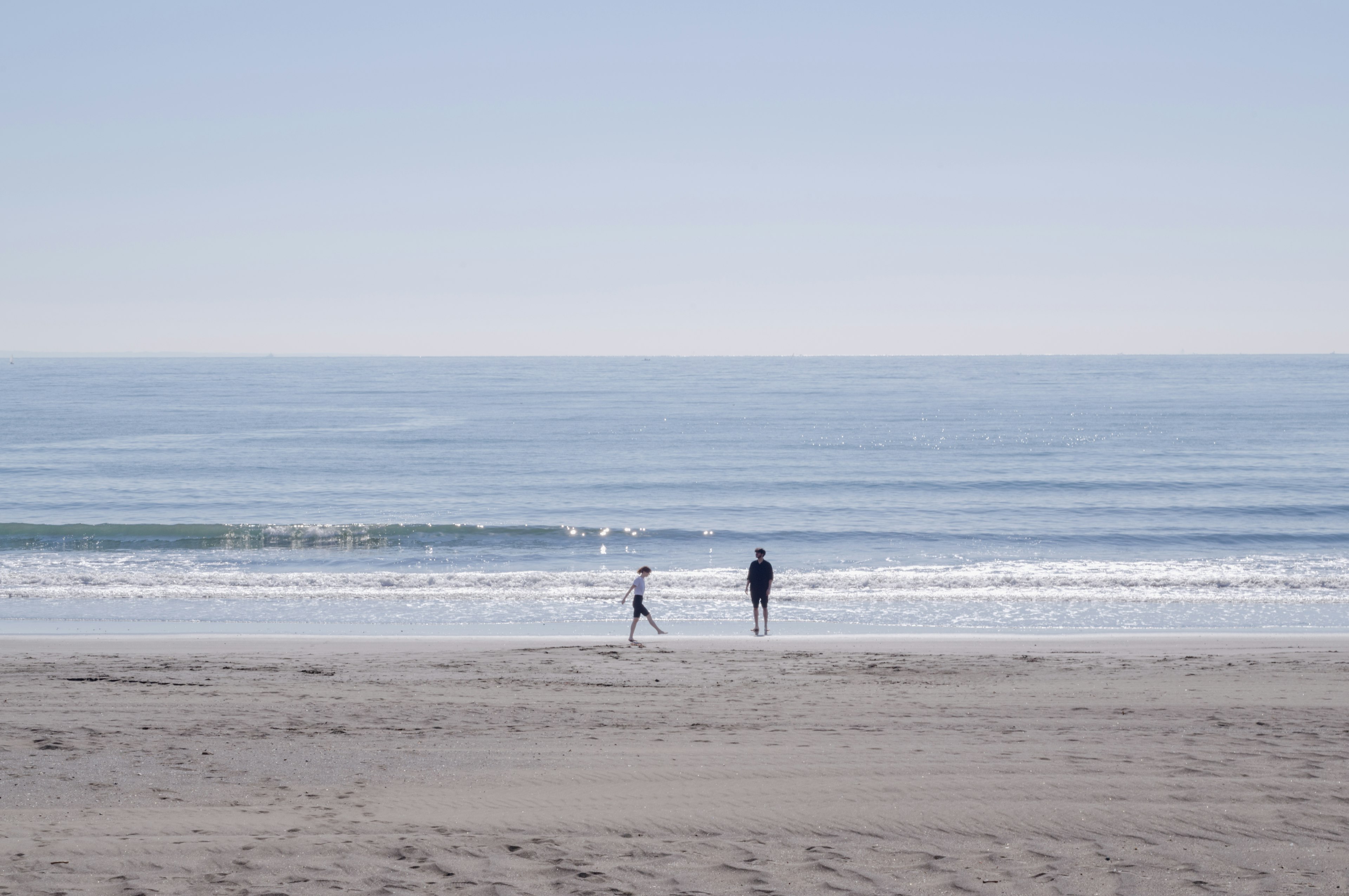 Silhouette of a parent and child playing by a calm sea