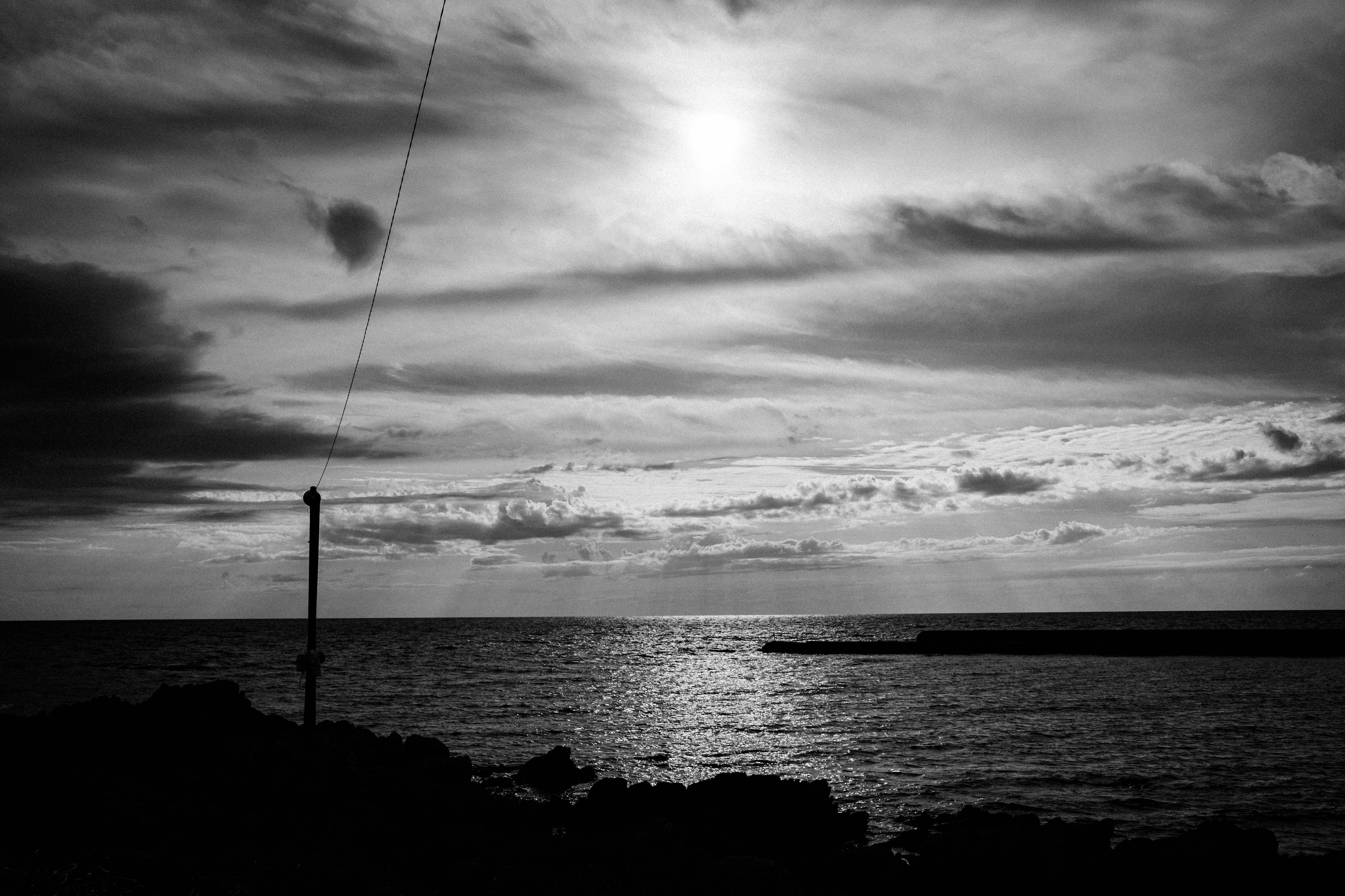 Paesaggio in bianco e nero che riflette il sole che tramonta sul mare