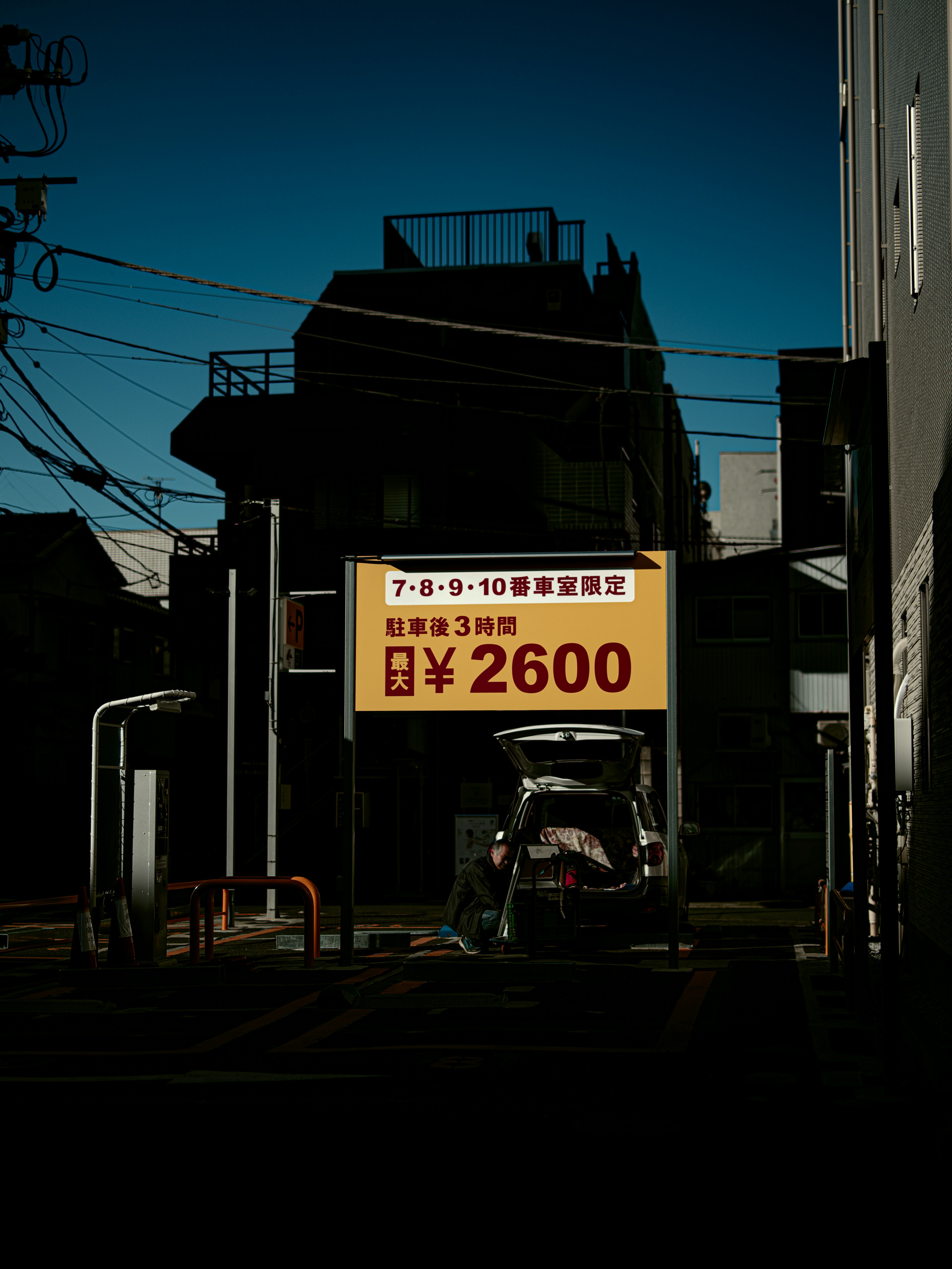 Yellow sign on a dark street corner with a car underneath