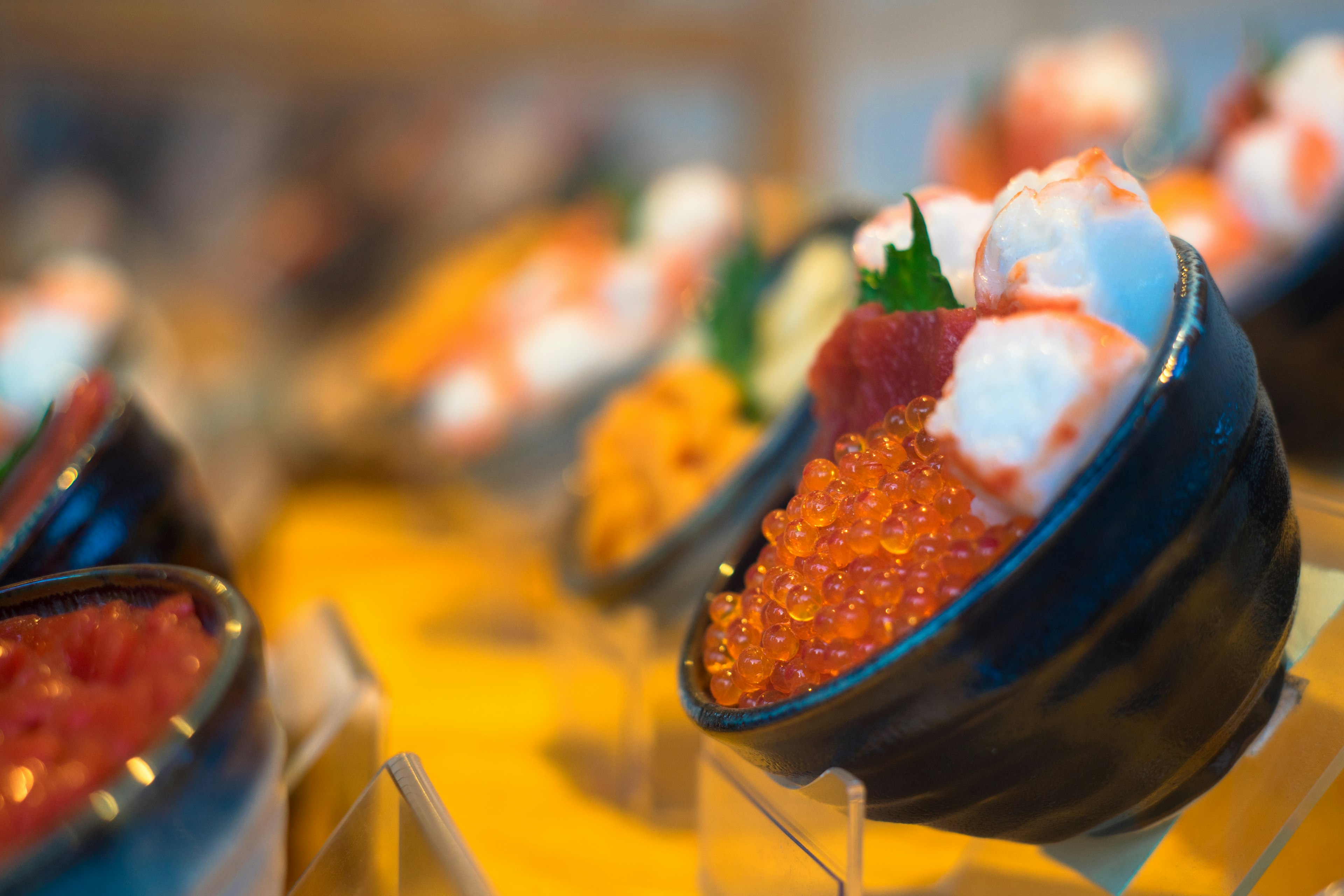 Fresh sushi with fish roe and toppings in black bowls