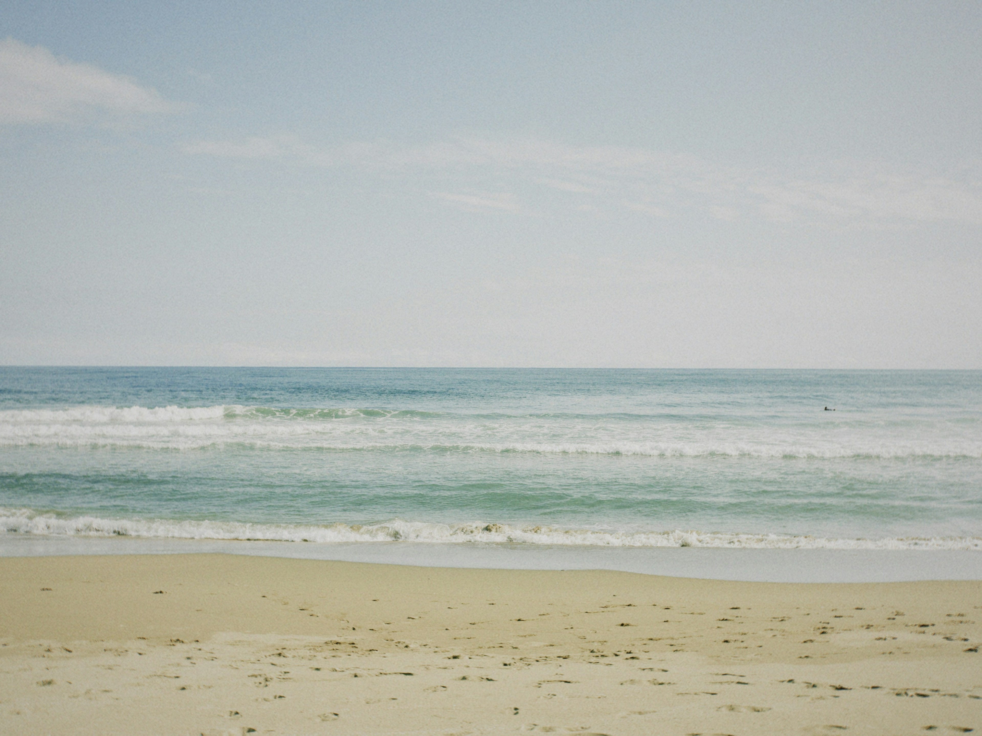 Scène de mer calme et de plage de sable avec de l'eau bleue et des vagues blanches