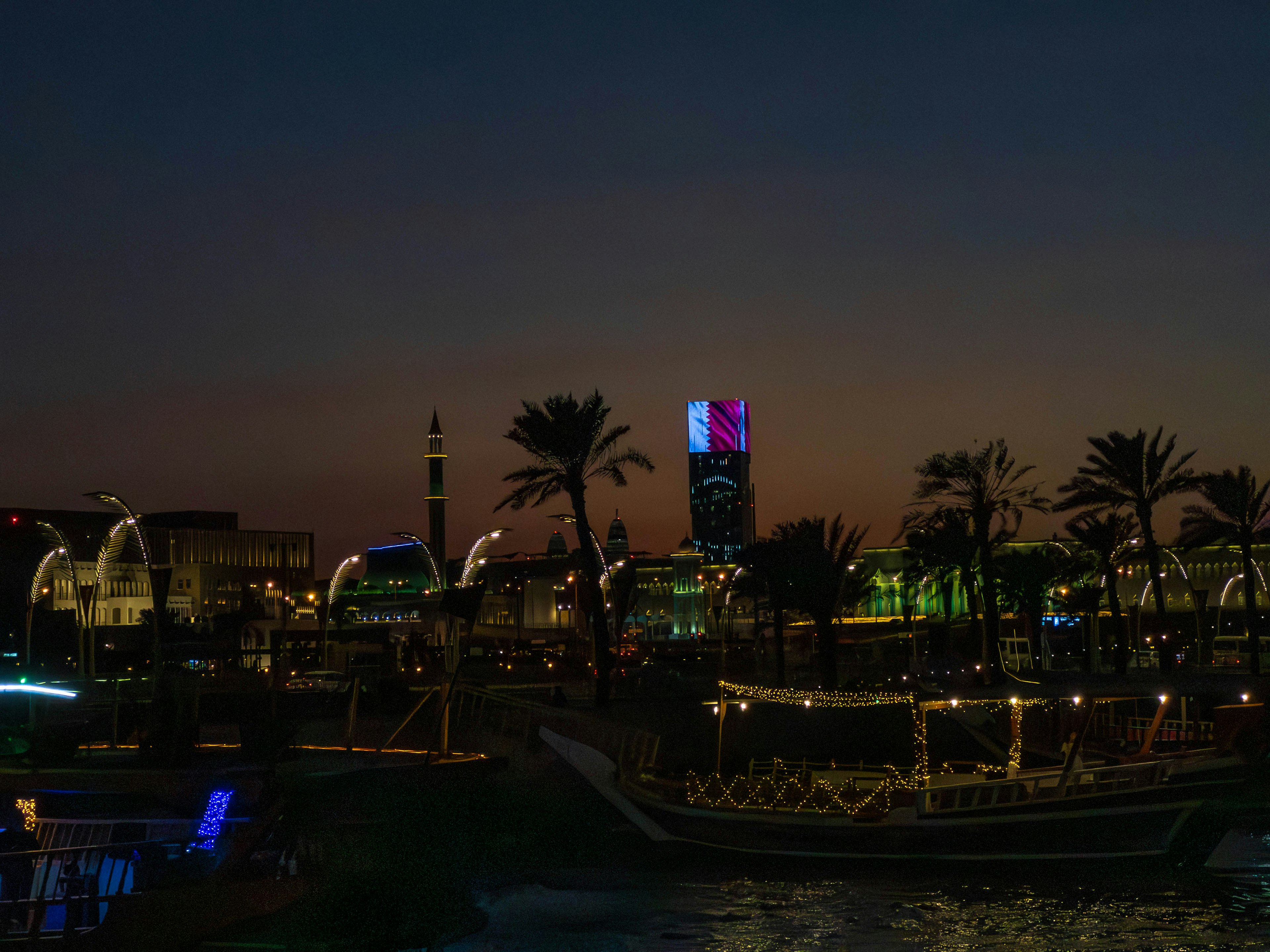 Night view of traditional boat on the waterfront with illuminated skyscrapers