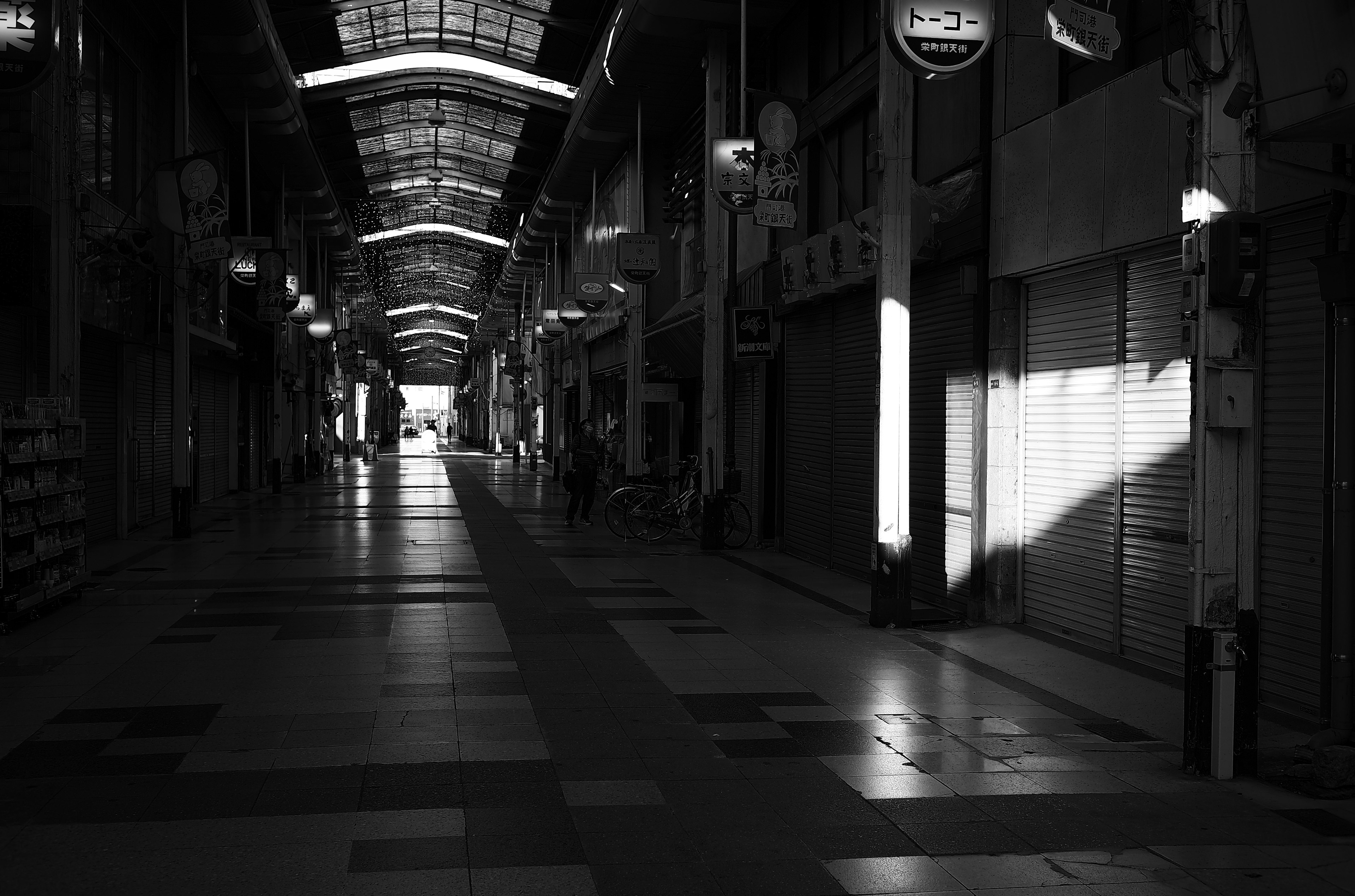 Pasillo largo y vacío de una calle comercial con luz que entra por el suelo