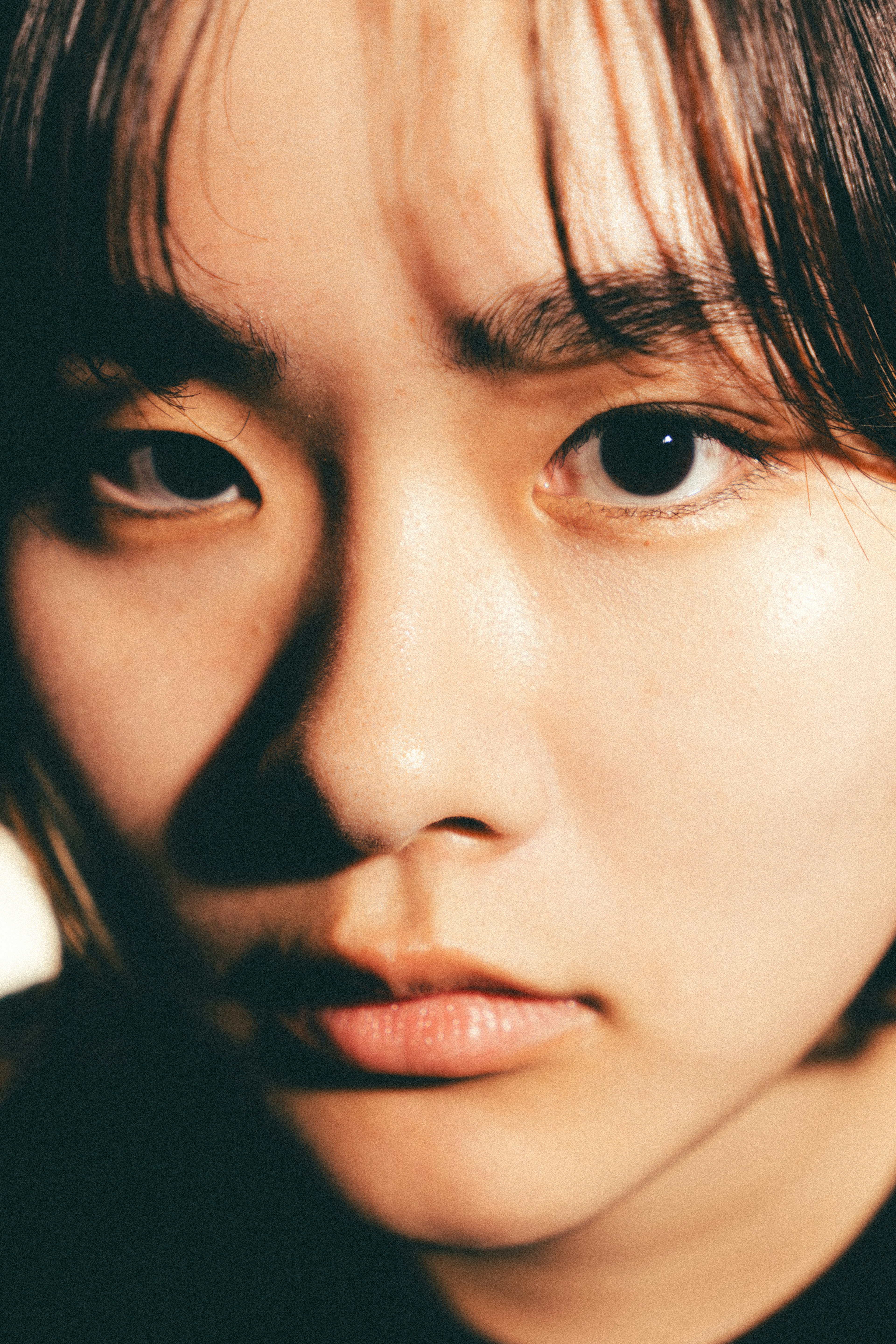 Photo en gros plan d'une jeune femme avec des yeux et une texture de peau mis en valeur sous un éclairage vif