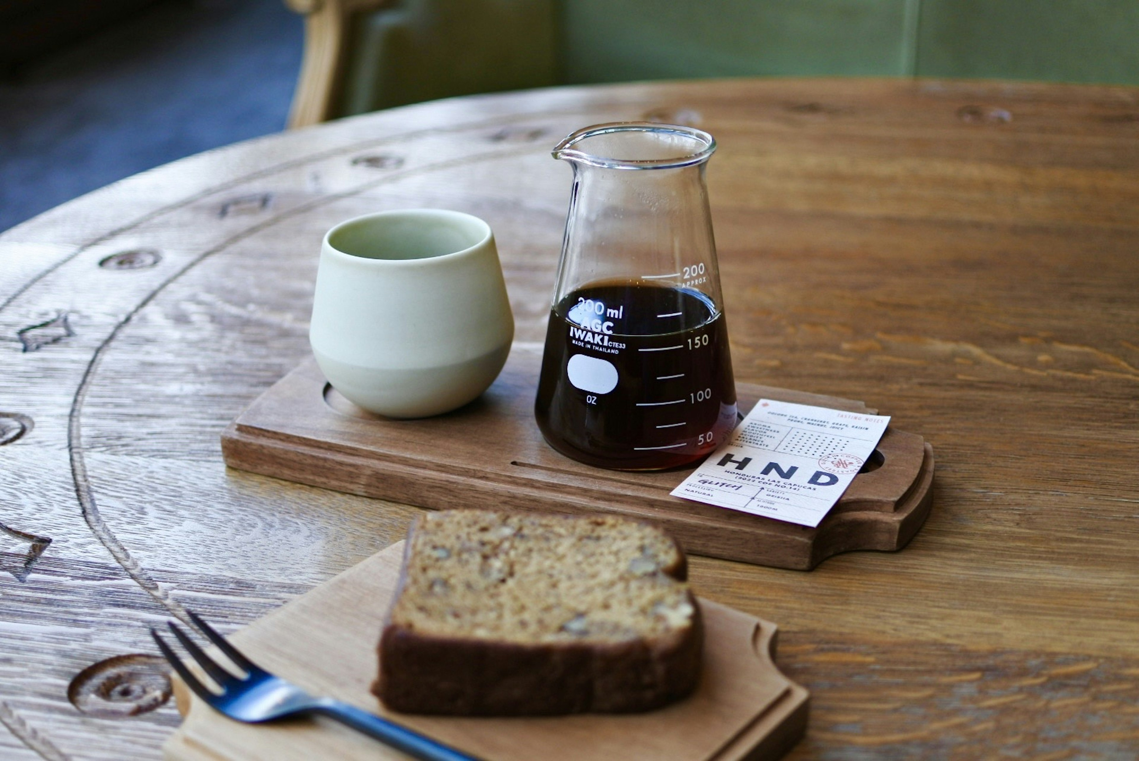 Escena con café, una taza verde y pan sobre una mesa de madera