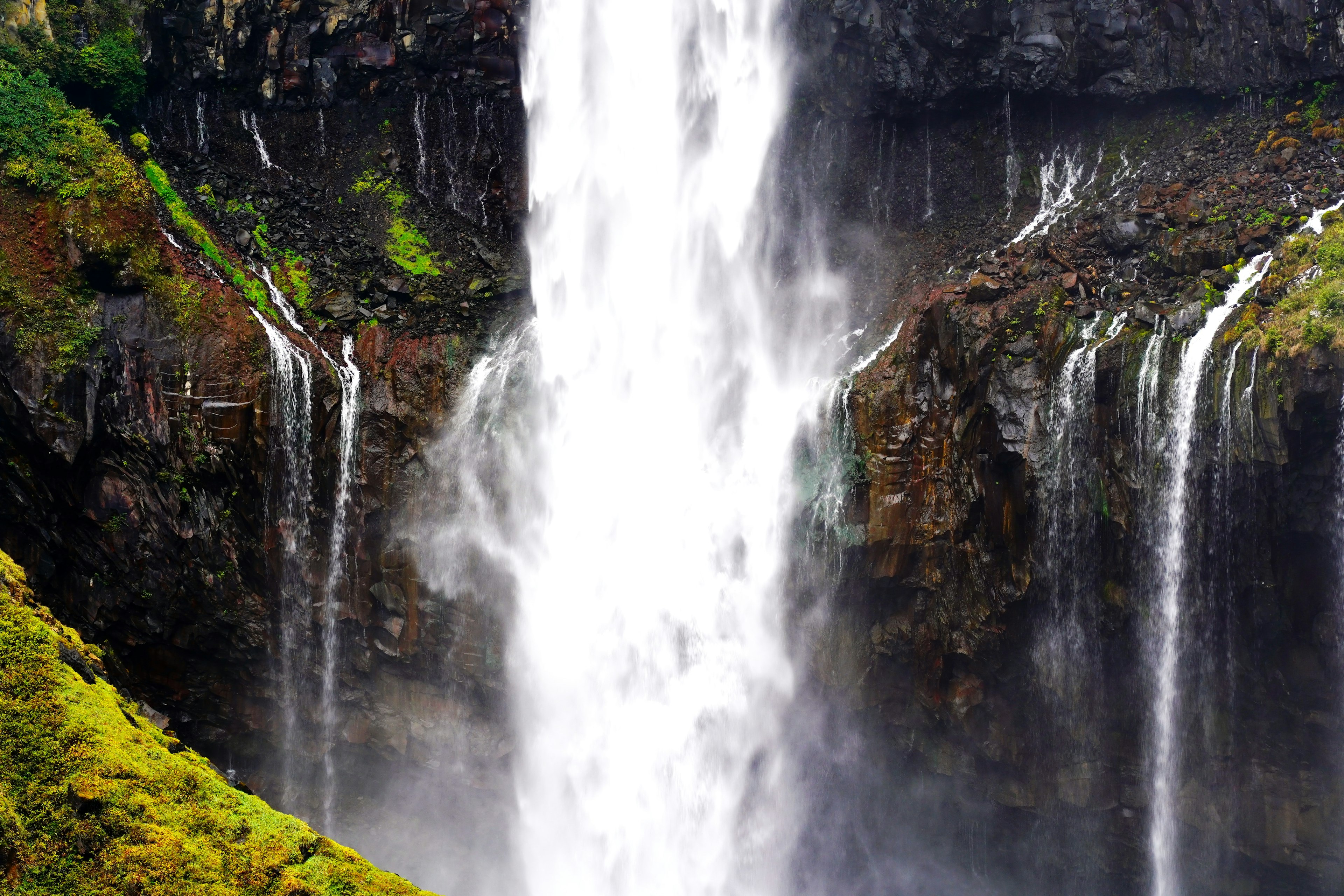 A stunning view of a large waterfall cascading down surrounded by lush greenery and rocky cliffs