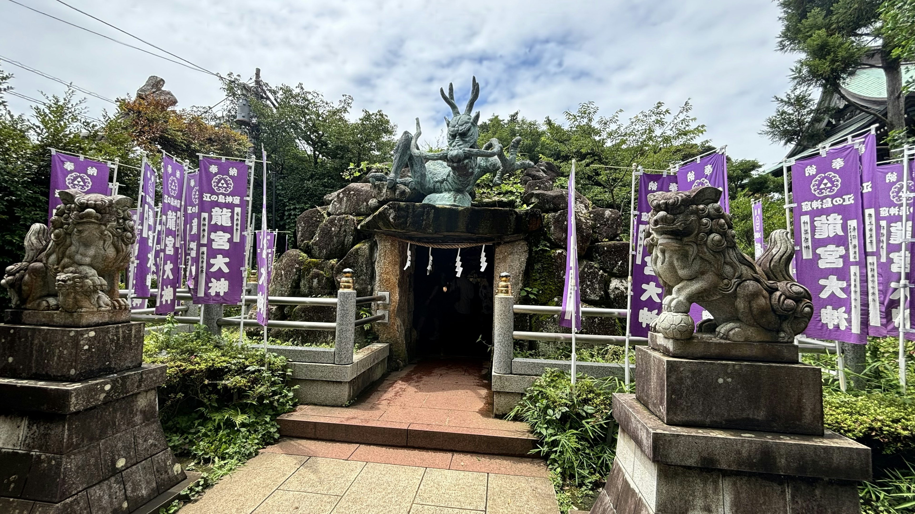 Entrance of a shrine featuring stone guardian lions and purple banners