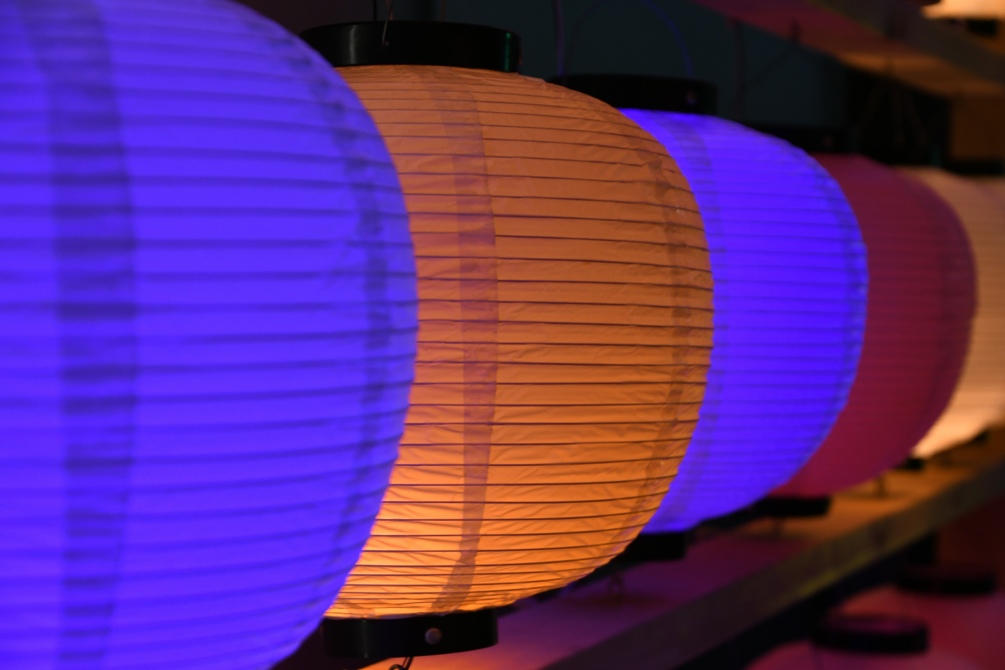 Colorful paper lanterns arranged in a row featuring shades of blue, purple, and orange