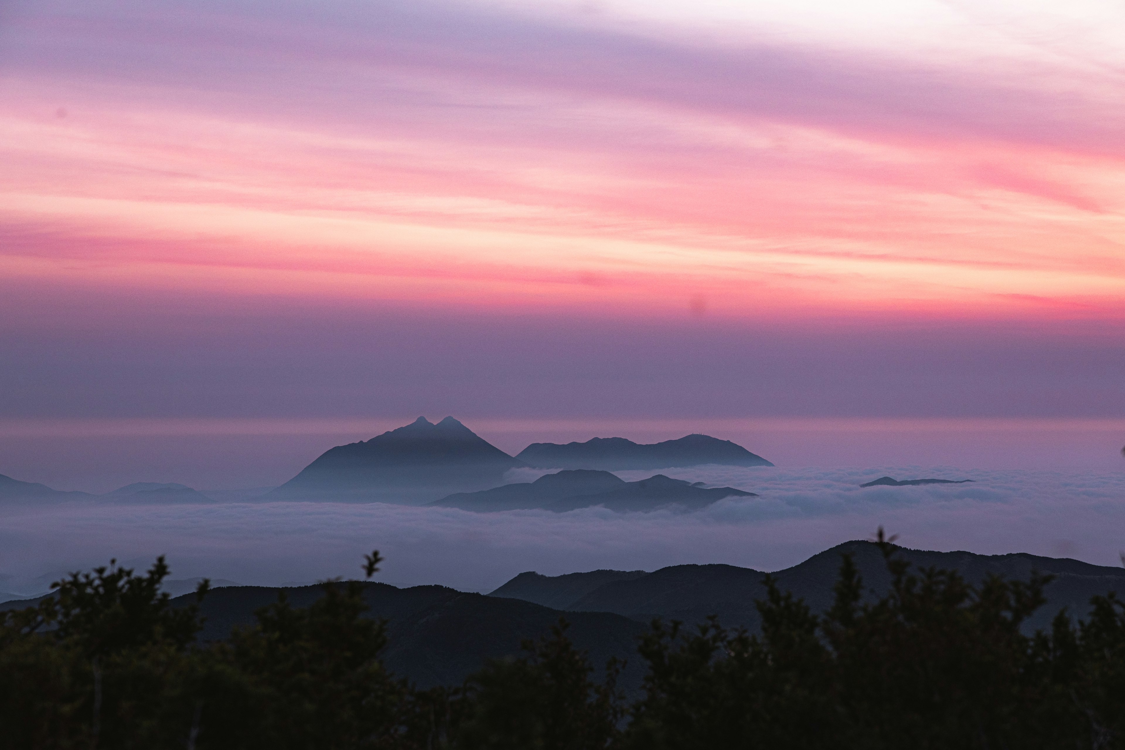 Pemandangan indah gunung di atas lautan awan saat matahari terbenam