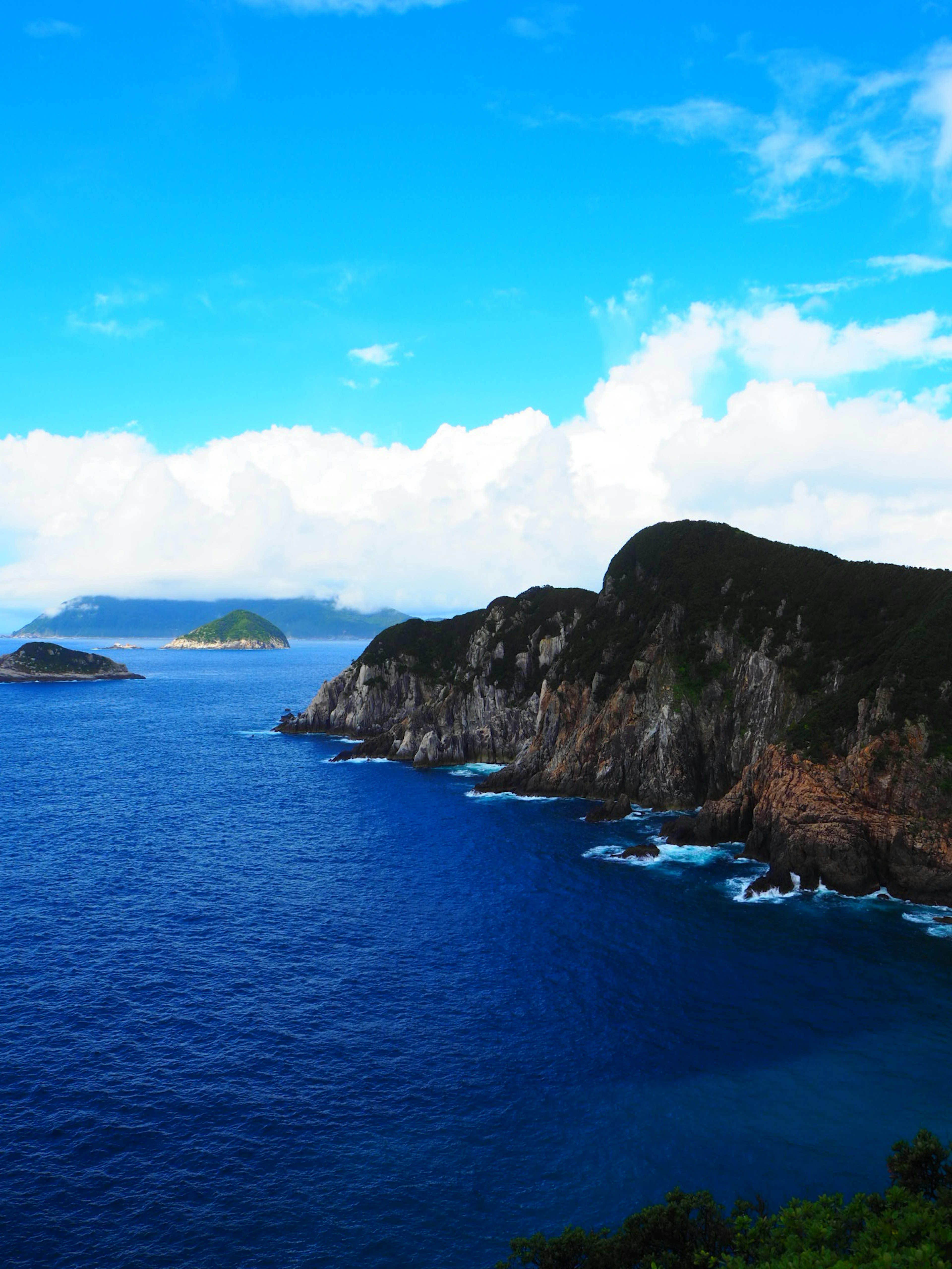 Vista escénica del océano azul con costa rocosa e islas distantes