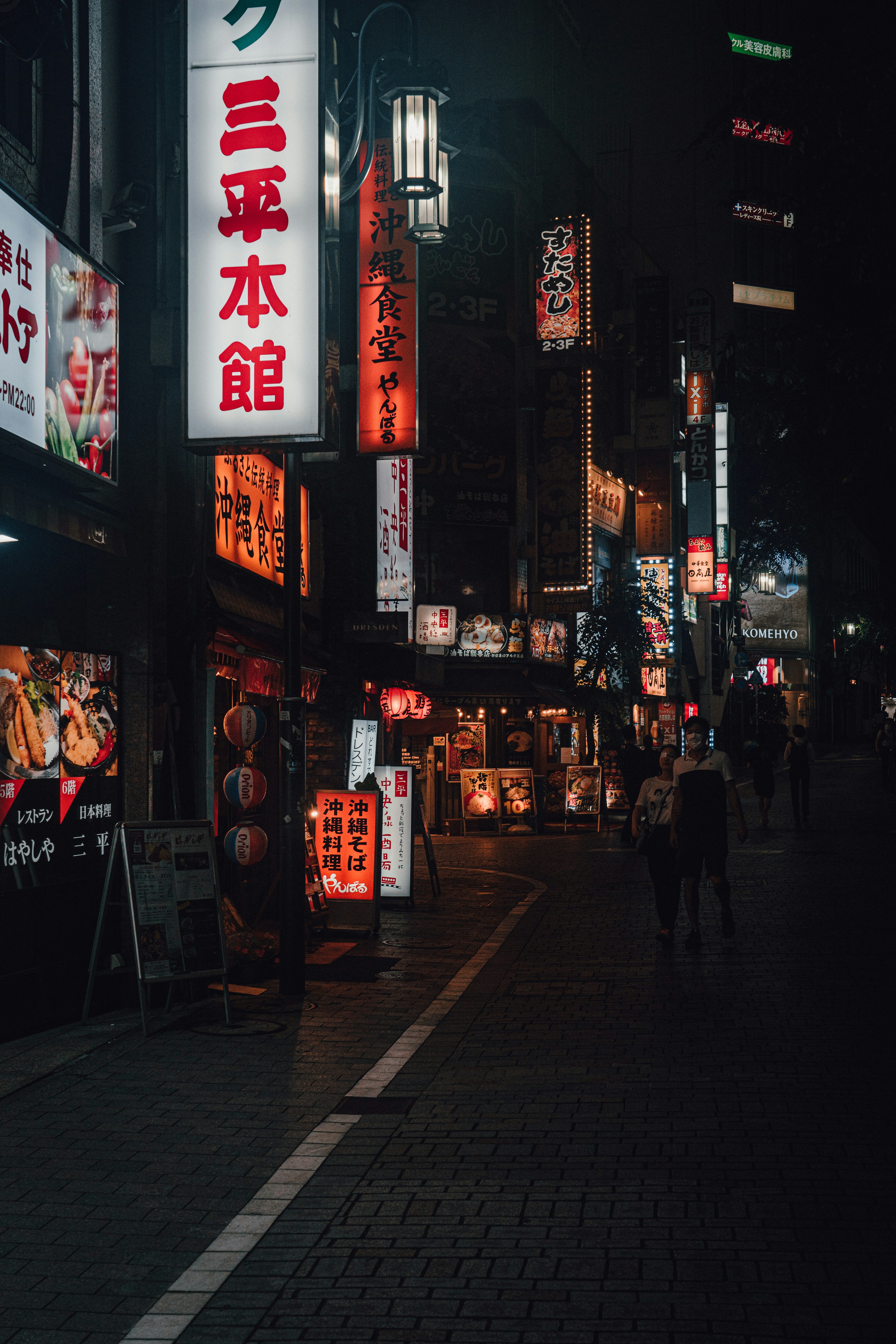 Escena de calle vibrante por la noche con letreros iluminados y peatones