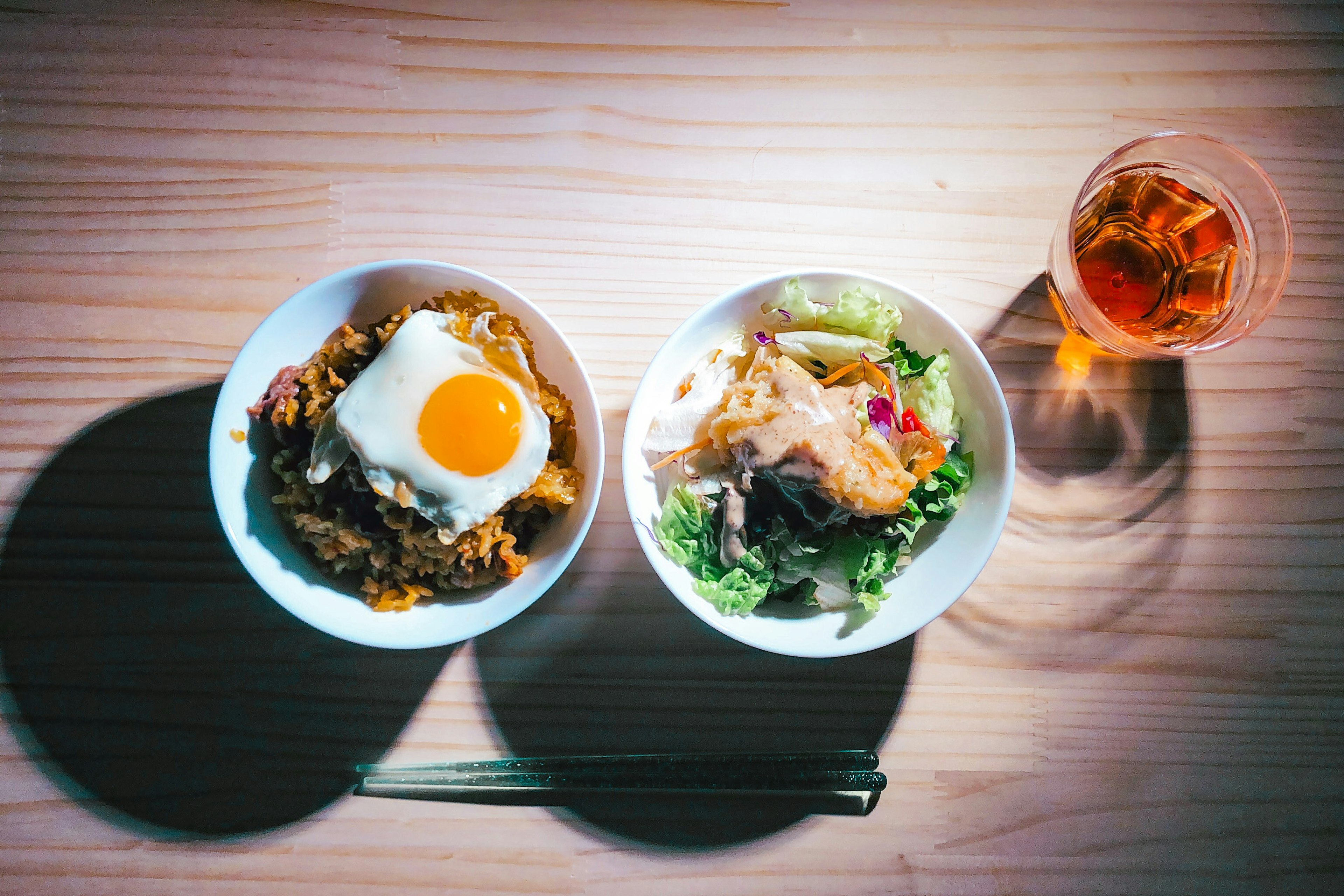 Overhead view of a meal with a bowl of rice topped with an egg and a salad