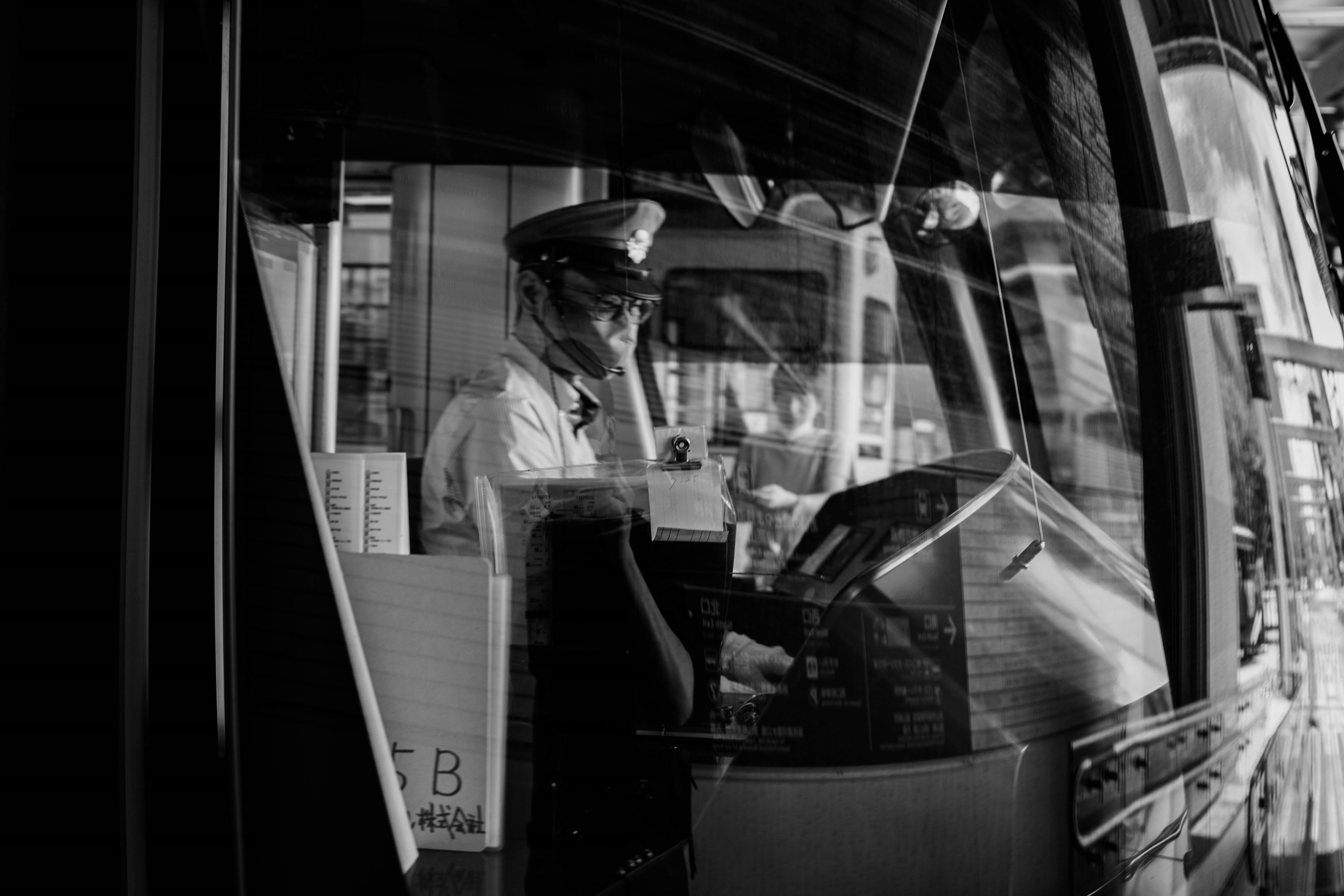 Foto hitam putih sopir bus bekerja di kursi pengemudi