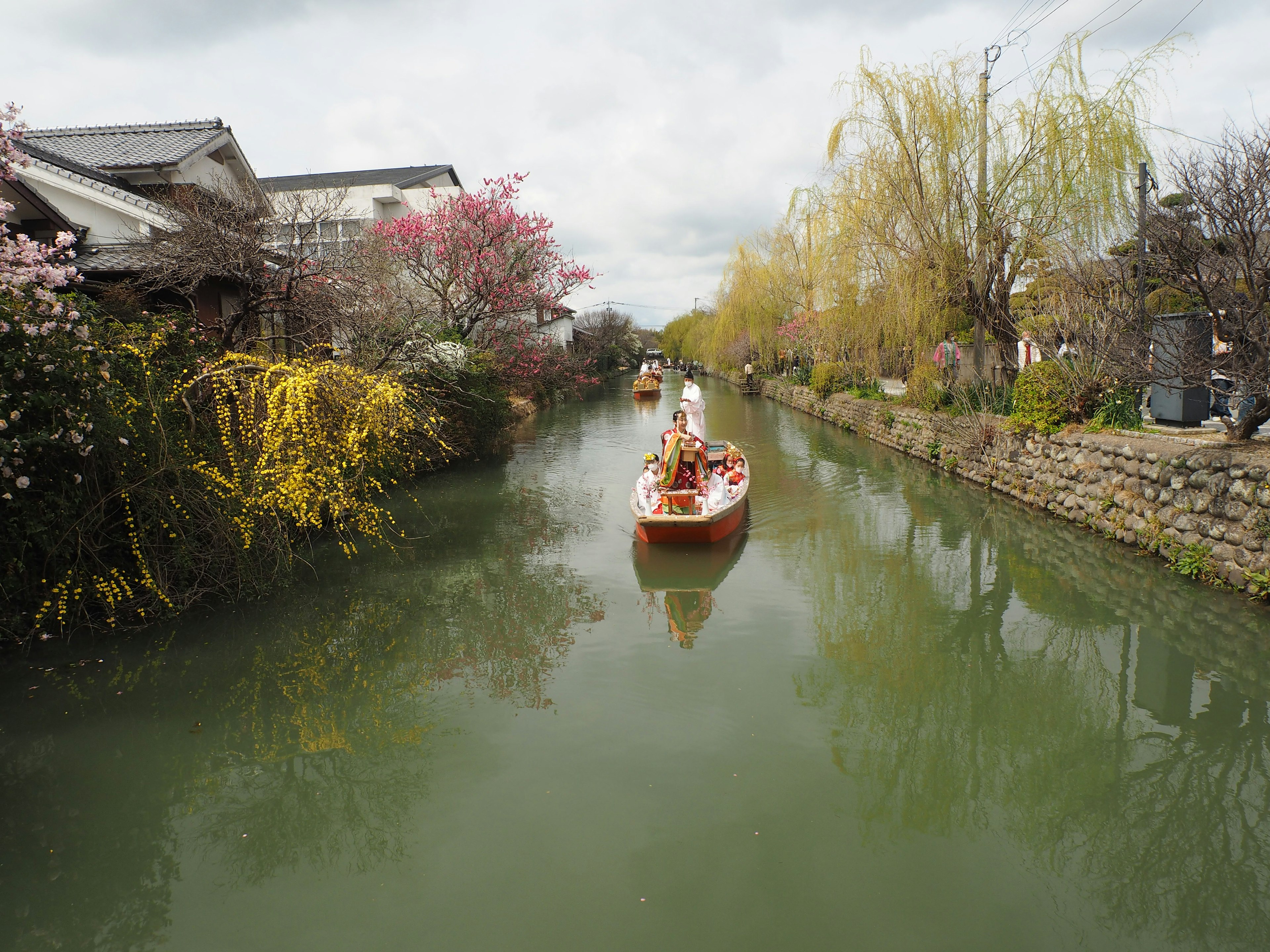 水路を進む小舟と春の花々が彩る風景