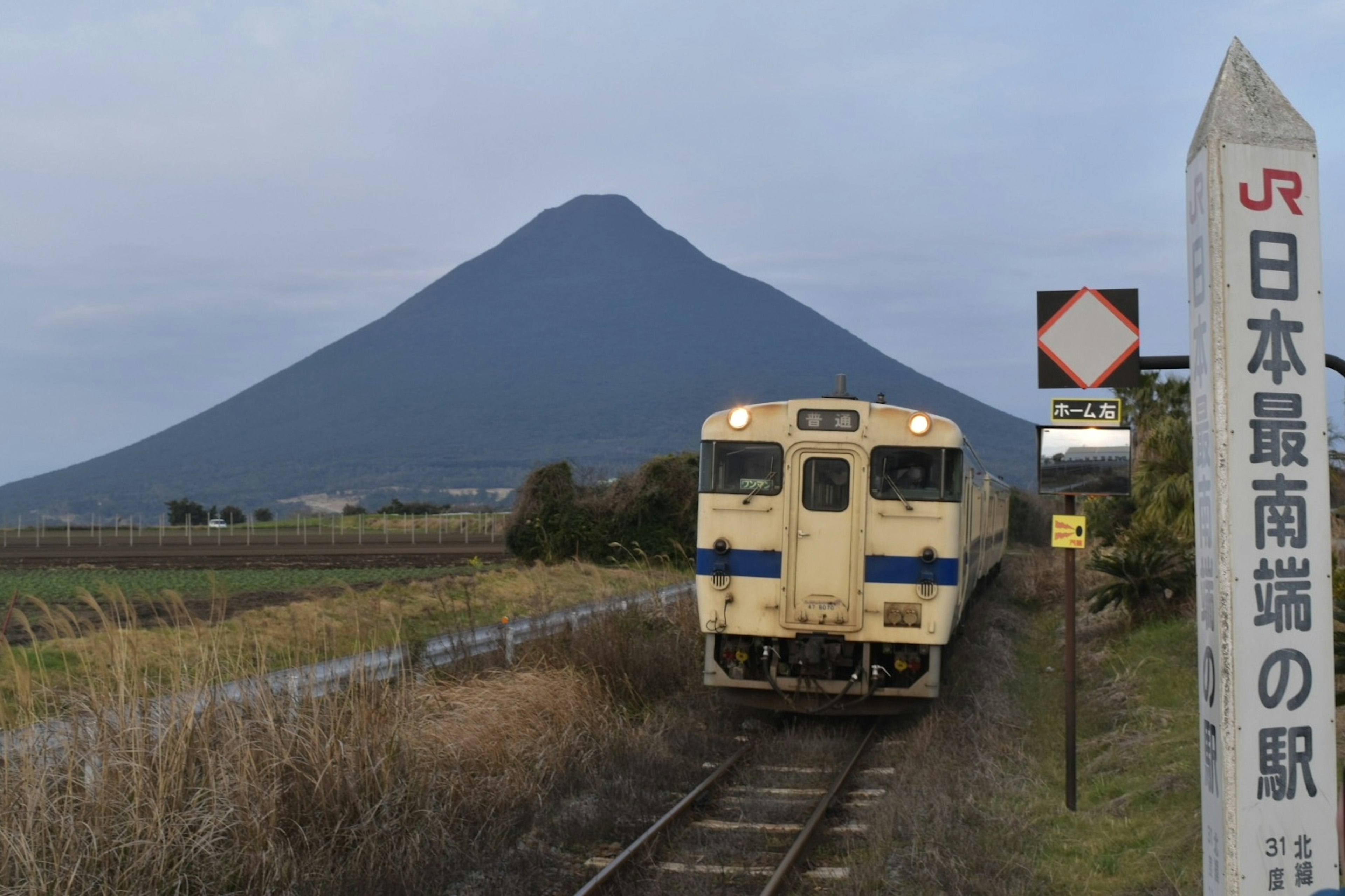 Train arrivant avec un arrière-plan de montagne et un panneau pour la station la plus au sud