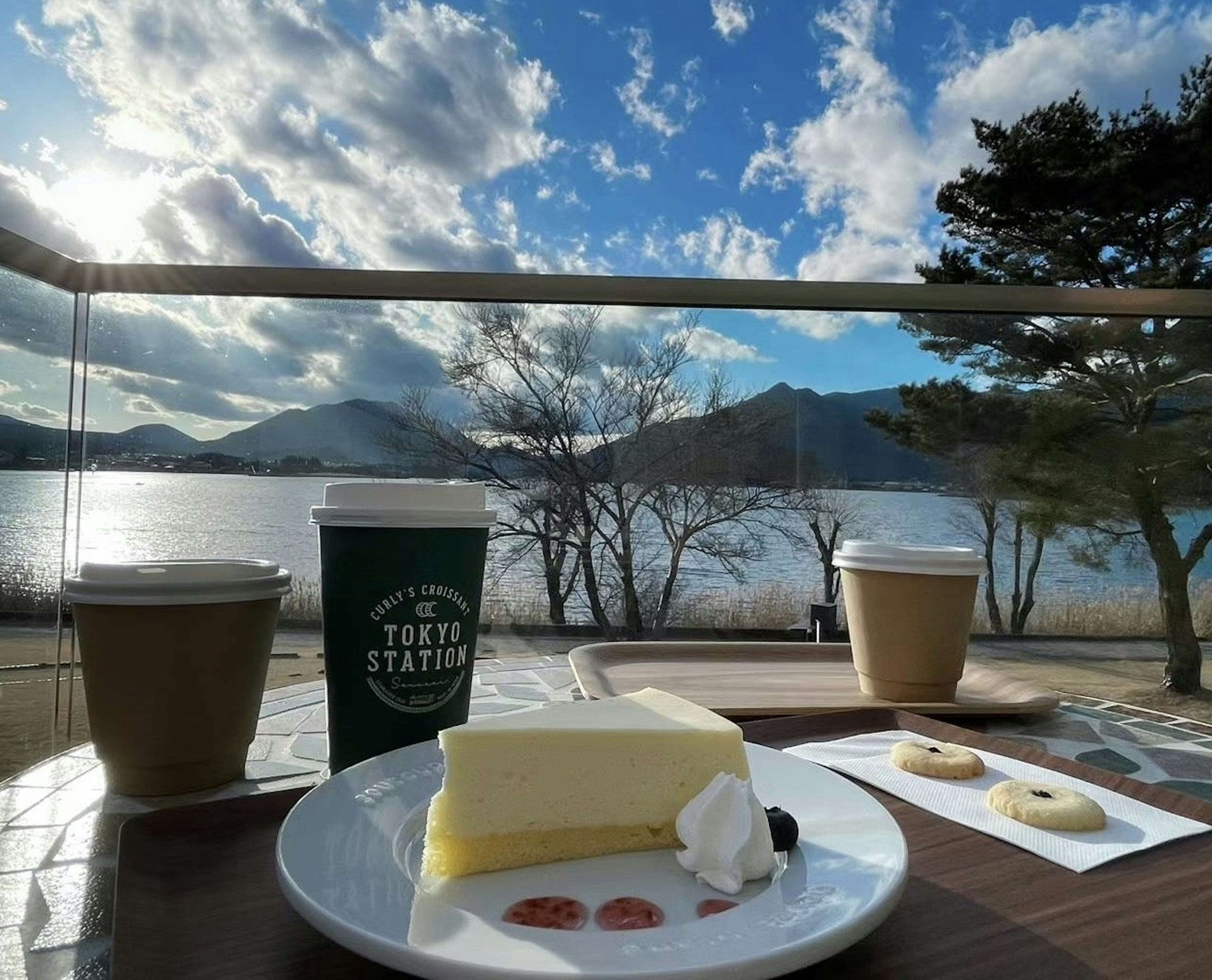 Cake and coffee on a table with a beautiful lake view in the background