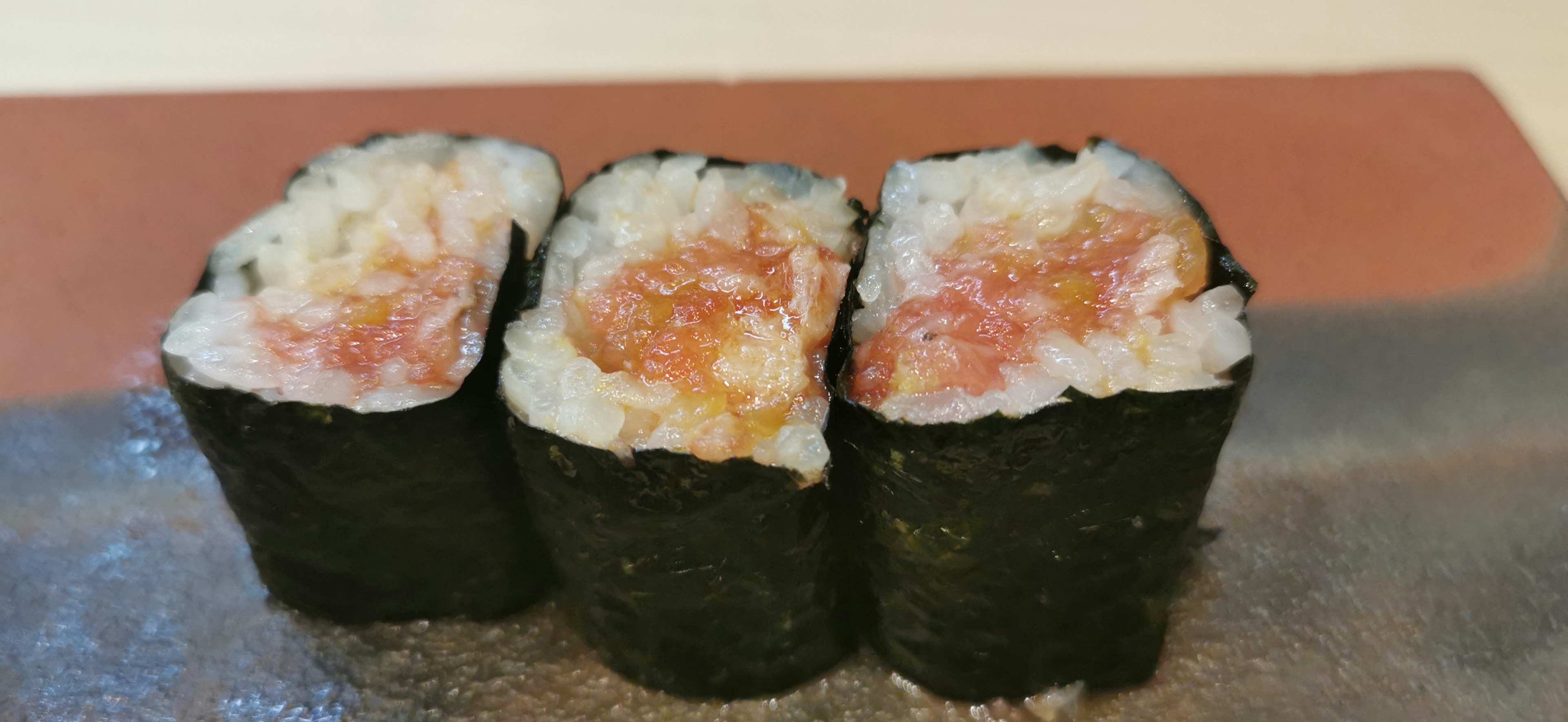 Three sushi rolls wrapped in black seaweed