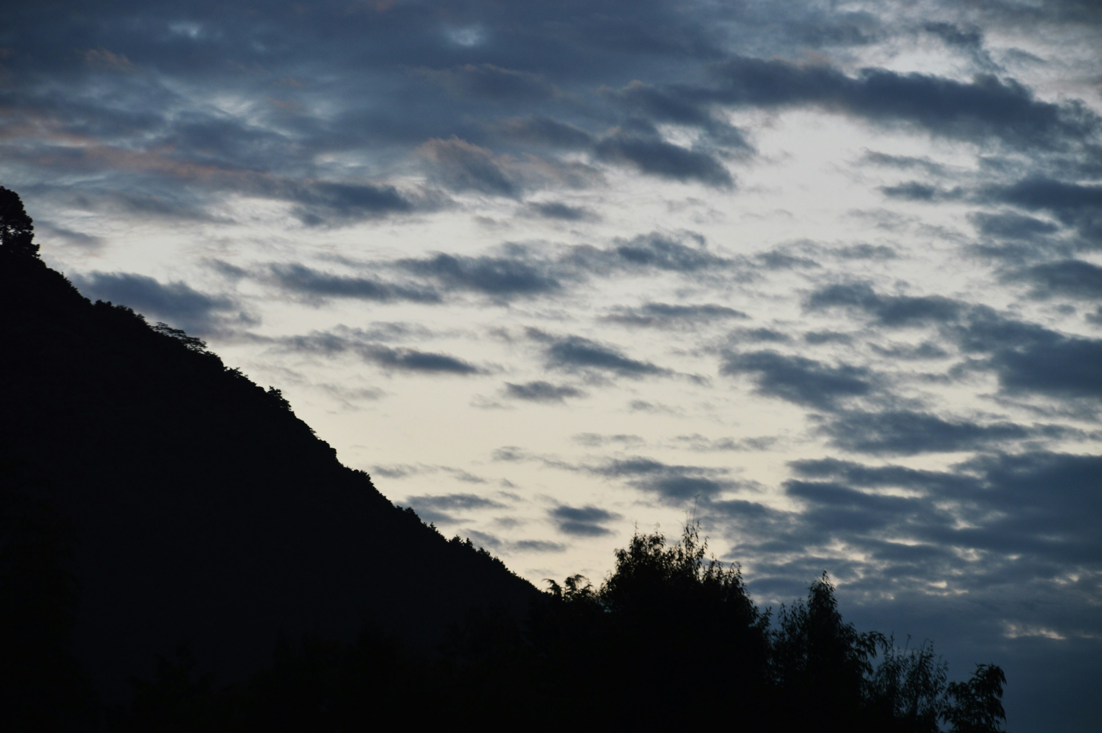 Silhouette eines Berges vor einem bewölkten Dämmerungshimmel