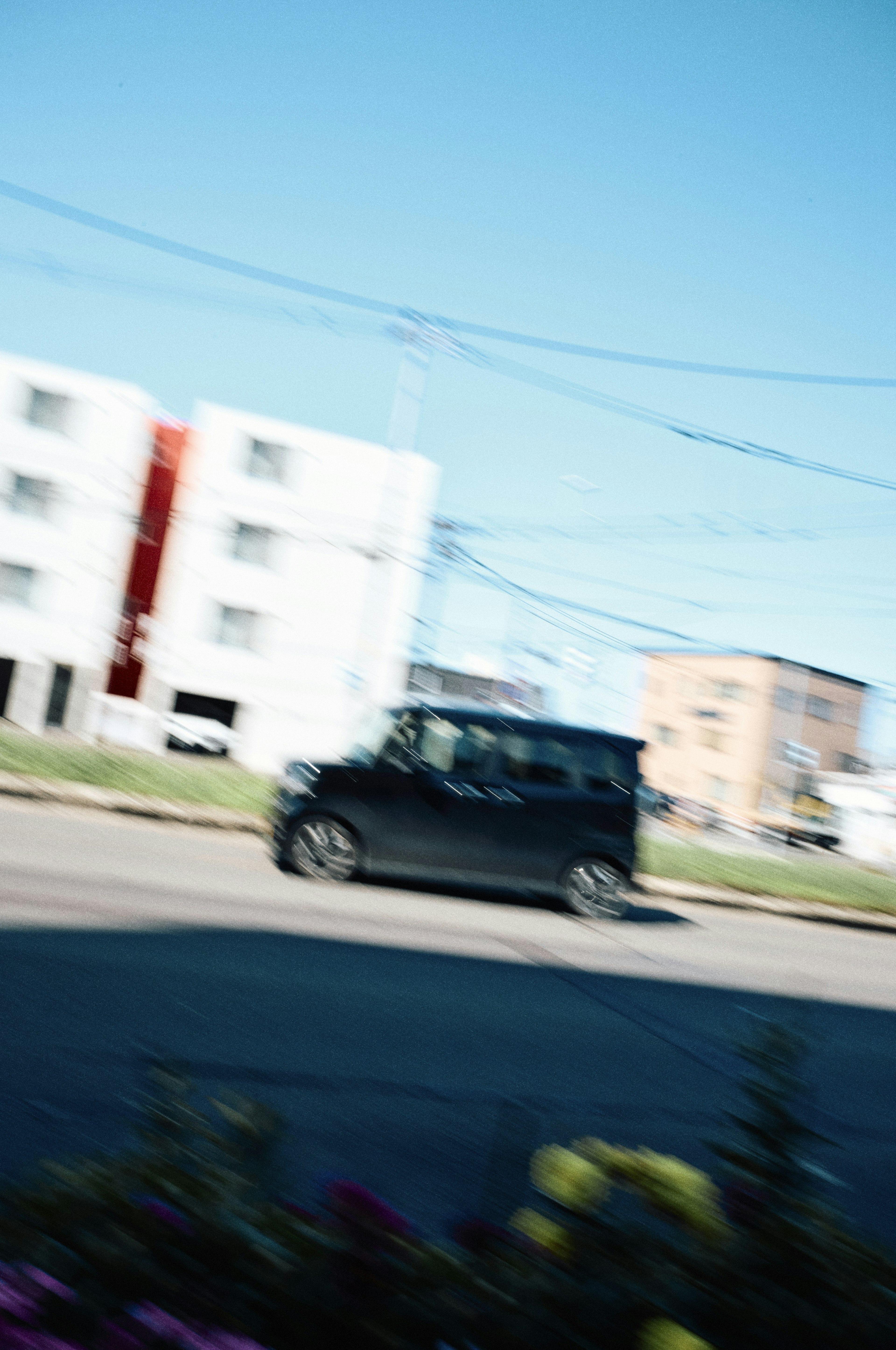 黒い車が通り過ぎる街の風景