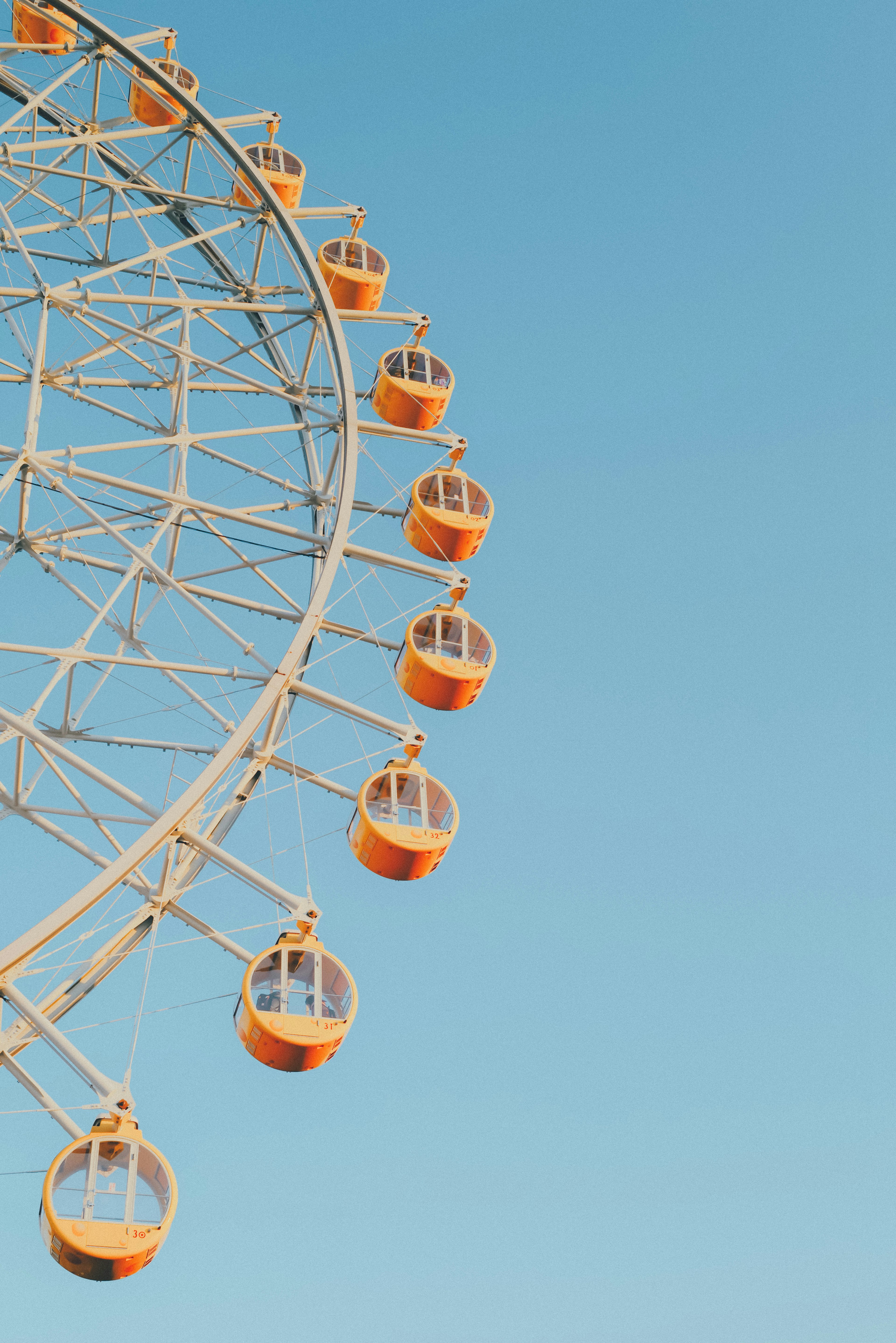 Kapsul roda ferris oranye di latar belakang langit biru