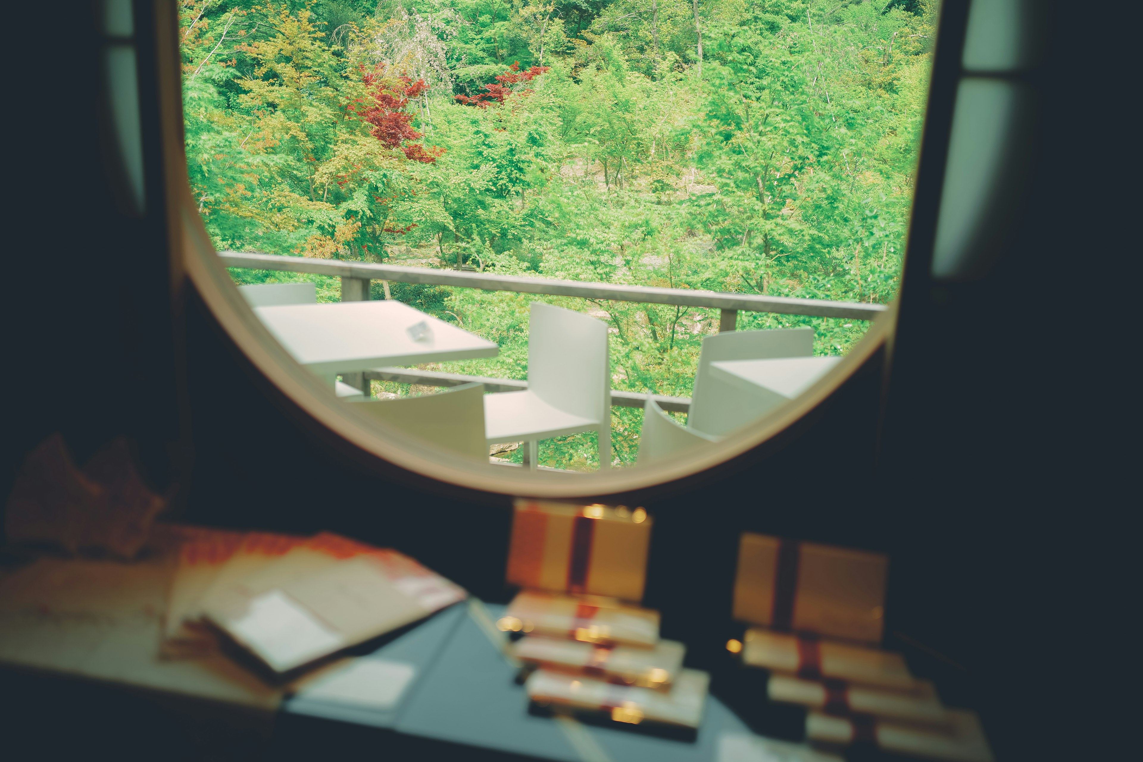 Round window showcasing lush greenery and outdoor seating