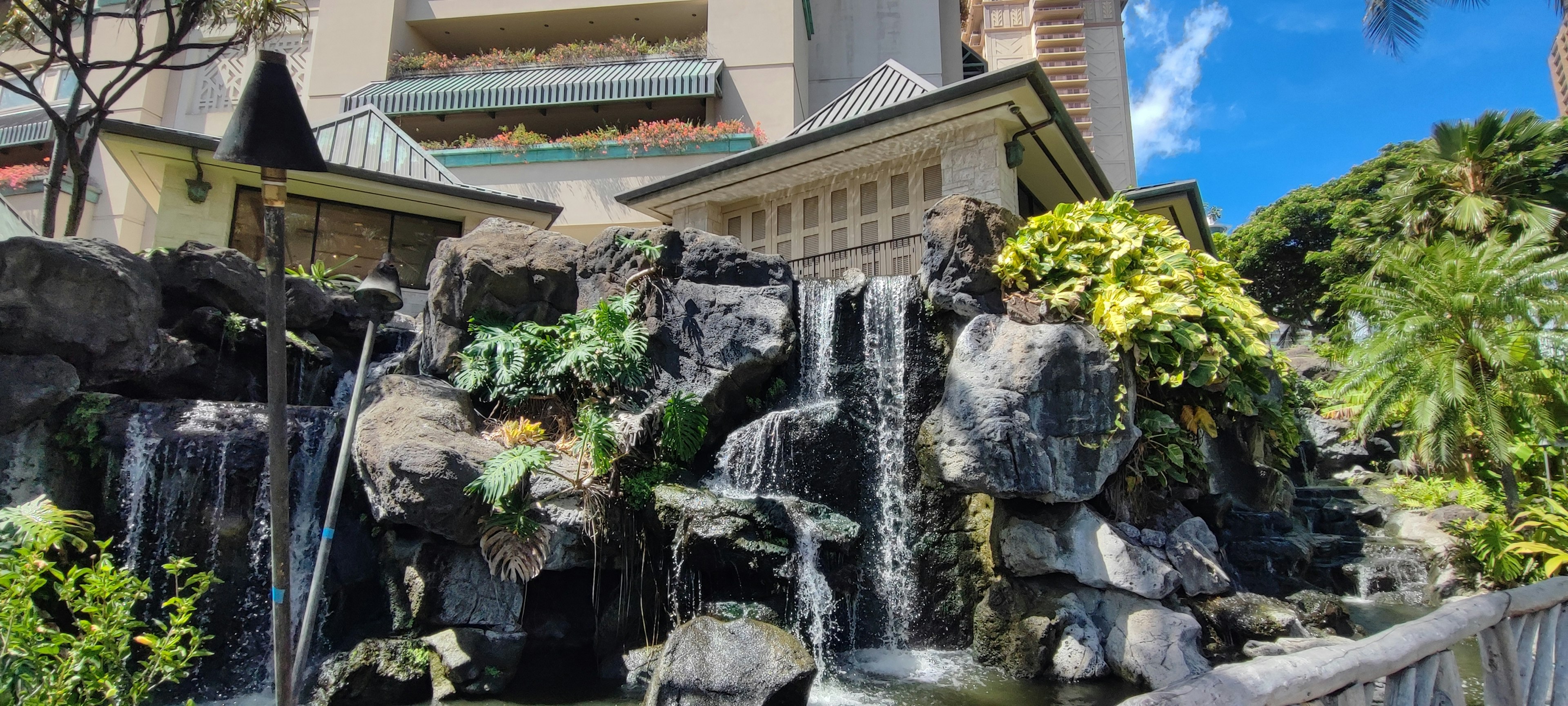 A beautiful waterfall with lush greenery near a building