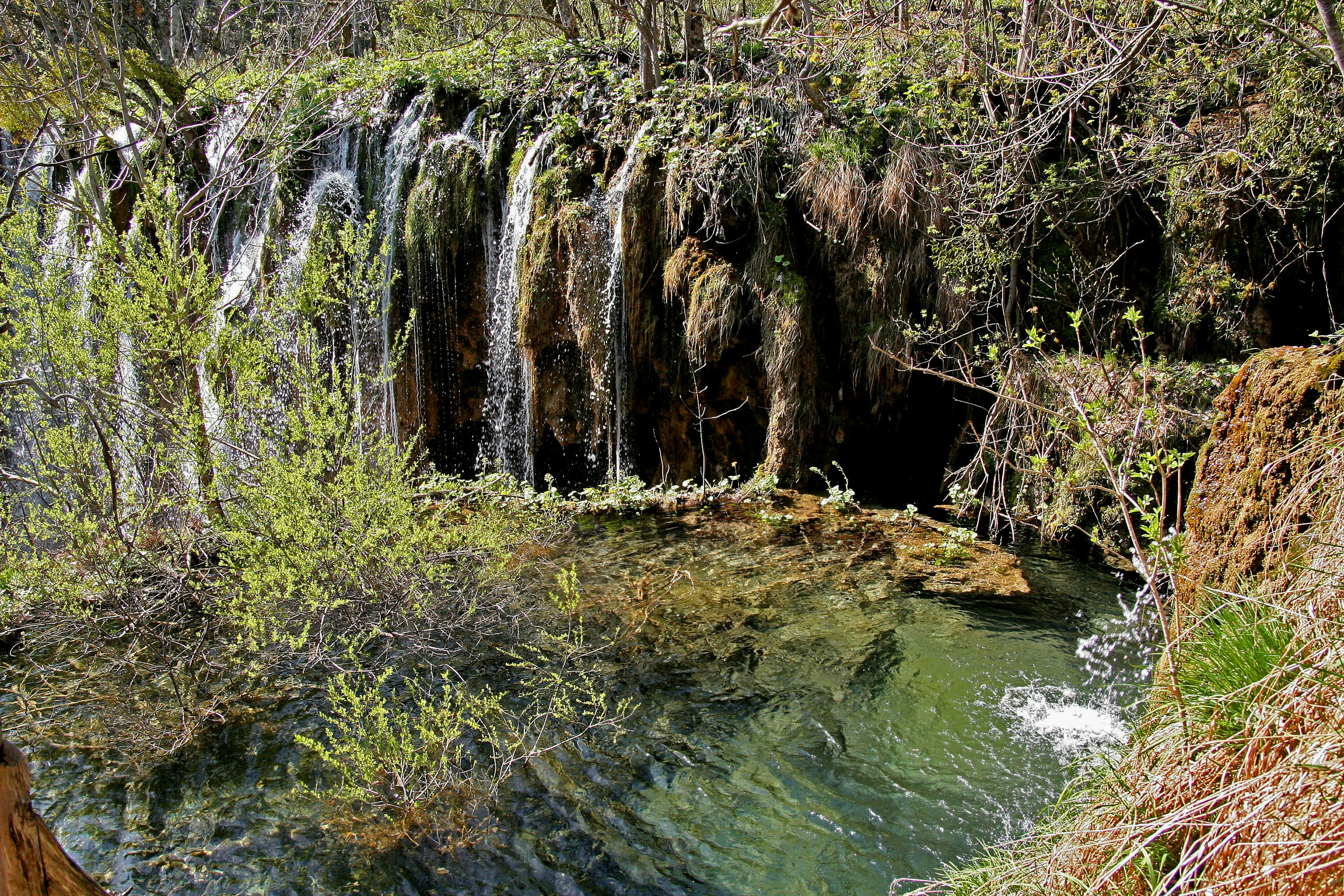 Ein ruhiger Wasserlauf umgeben von einem Wasserfall und üppigem Grün