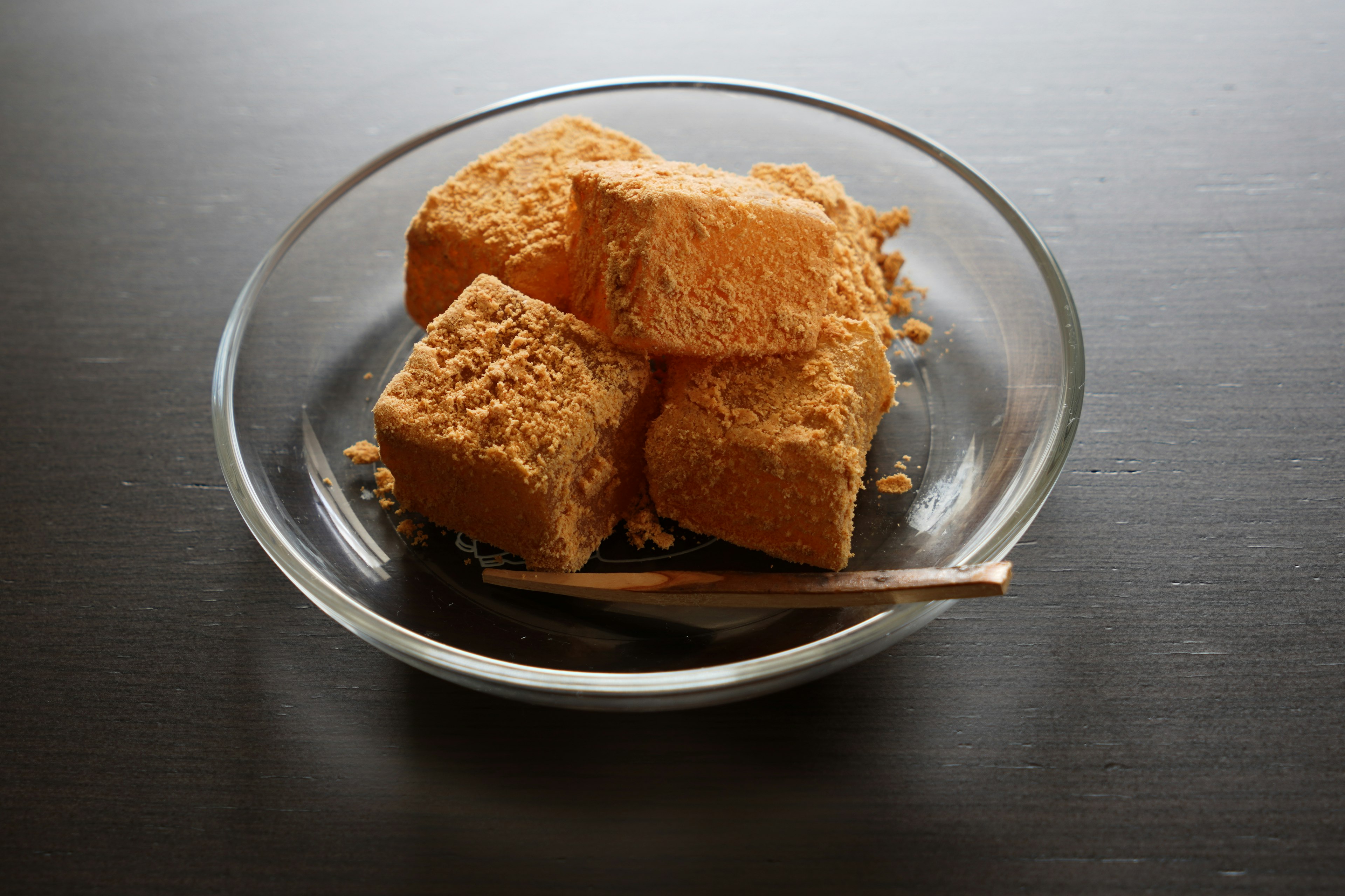 Orange-colored food resembling tofu on a small plate