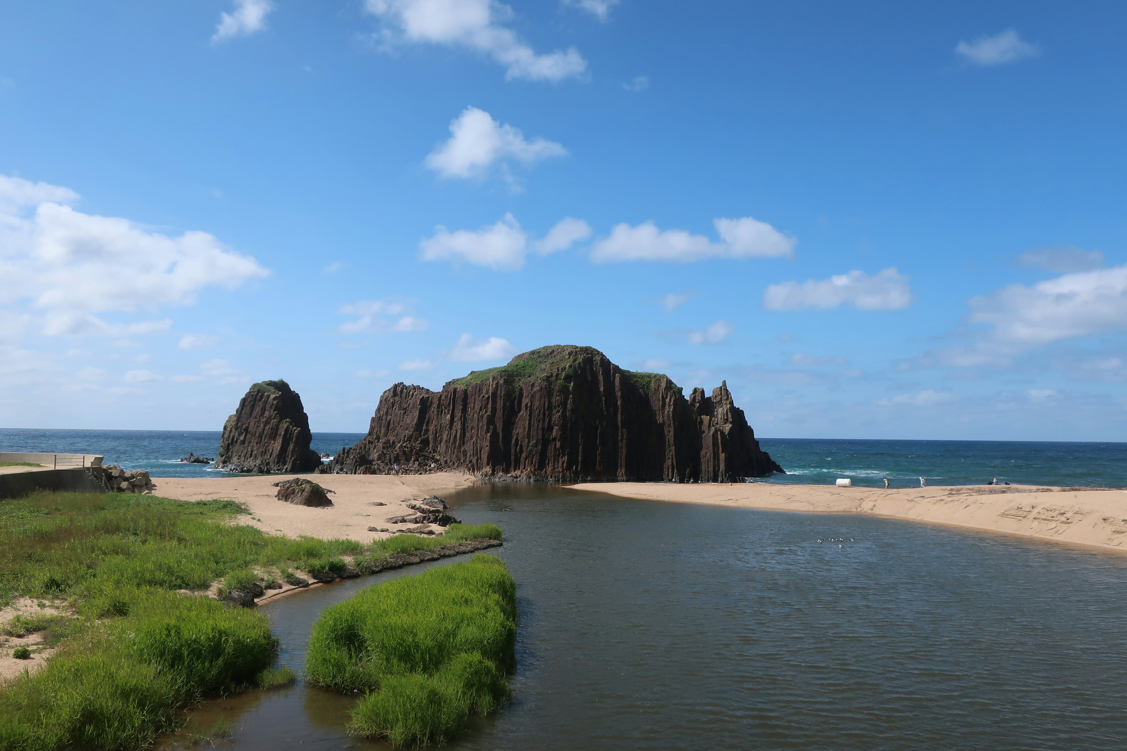 Rocky island surrounded by blue sky and sea with sandy beach