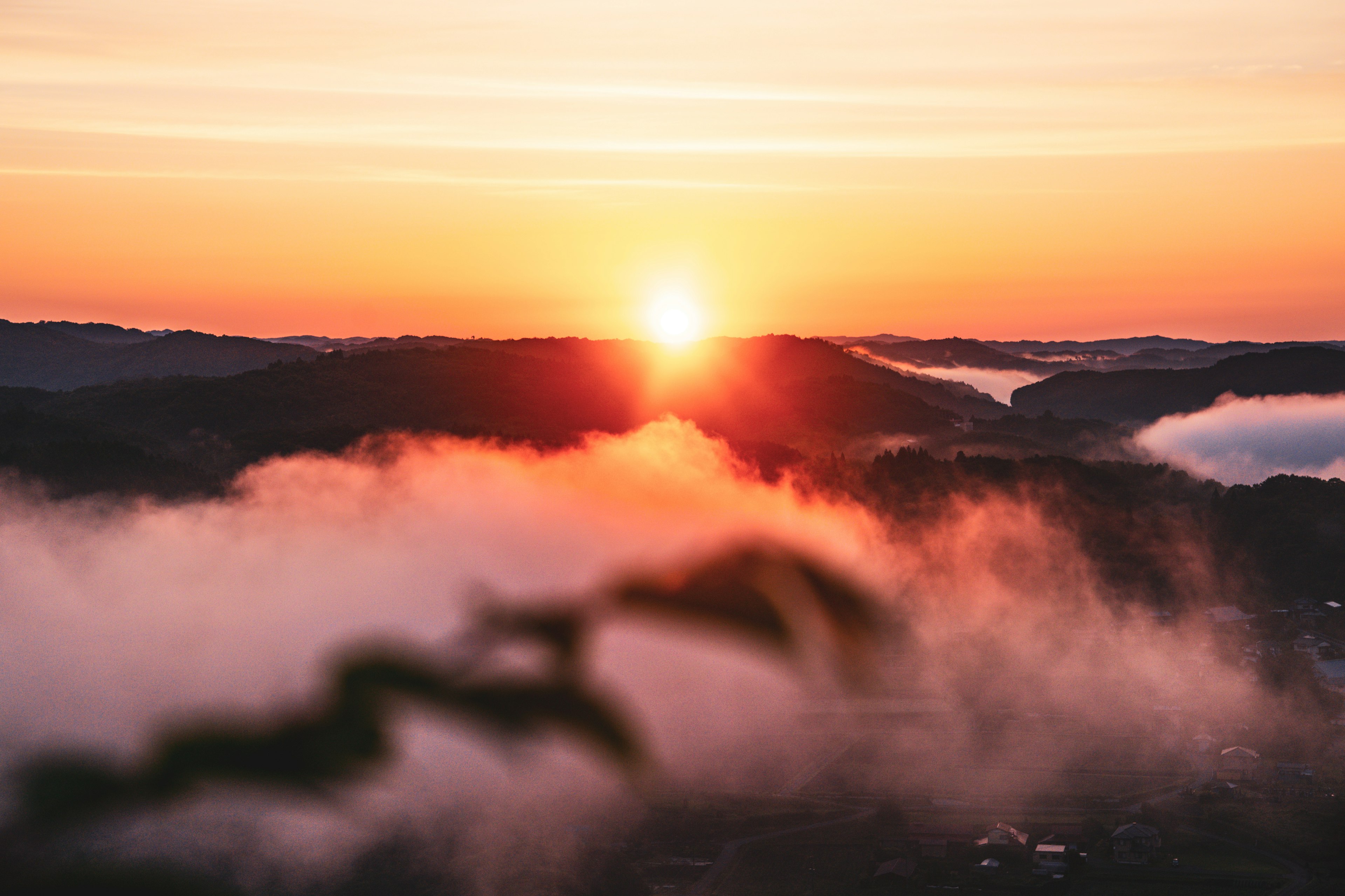 Beautiful sunset behind the mountains with thick fog covering the valley and soft light spreading