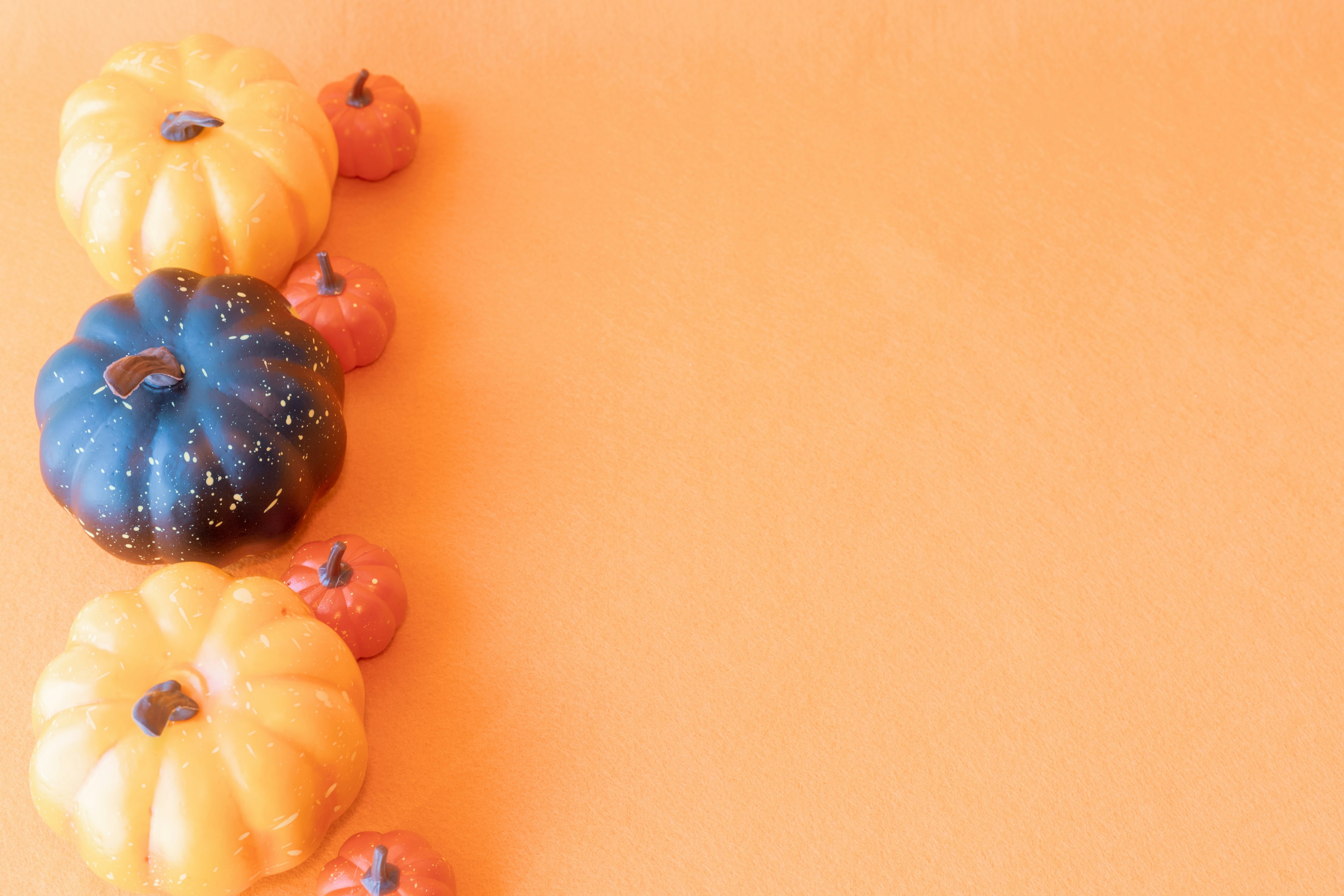 Des citrouilles colorées disposées sur un fond orange