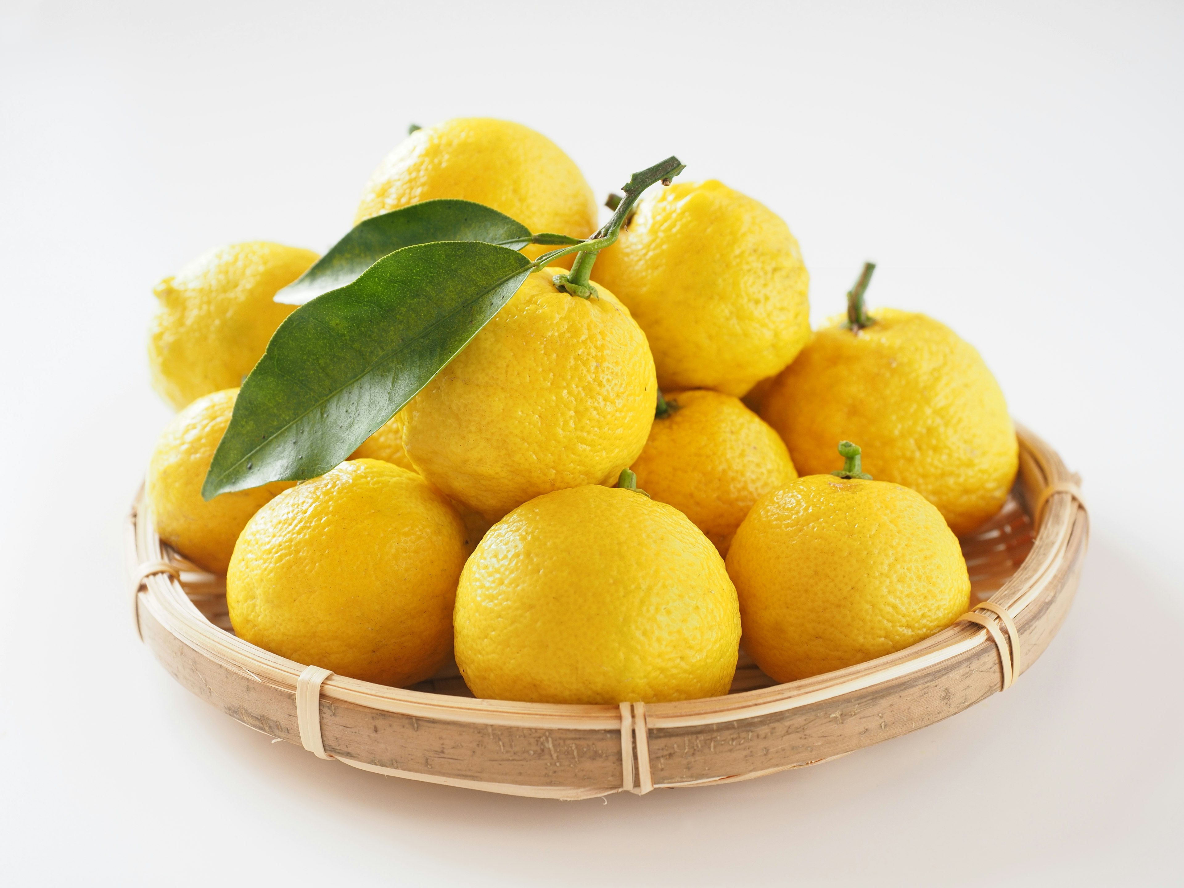 A bamboo basket filled with bright yellow citrus fruits