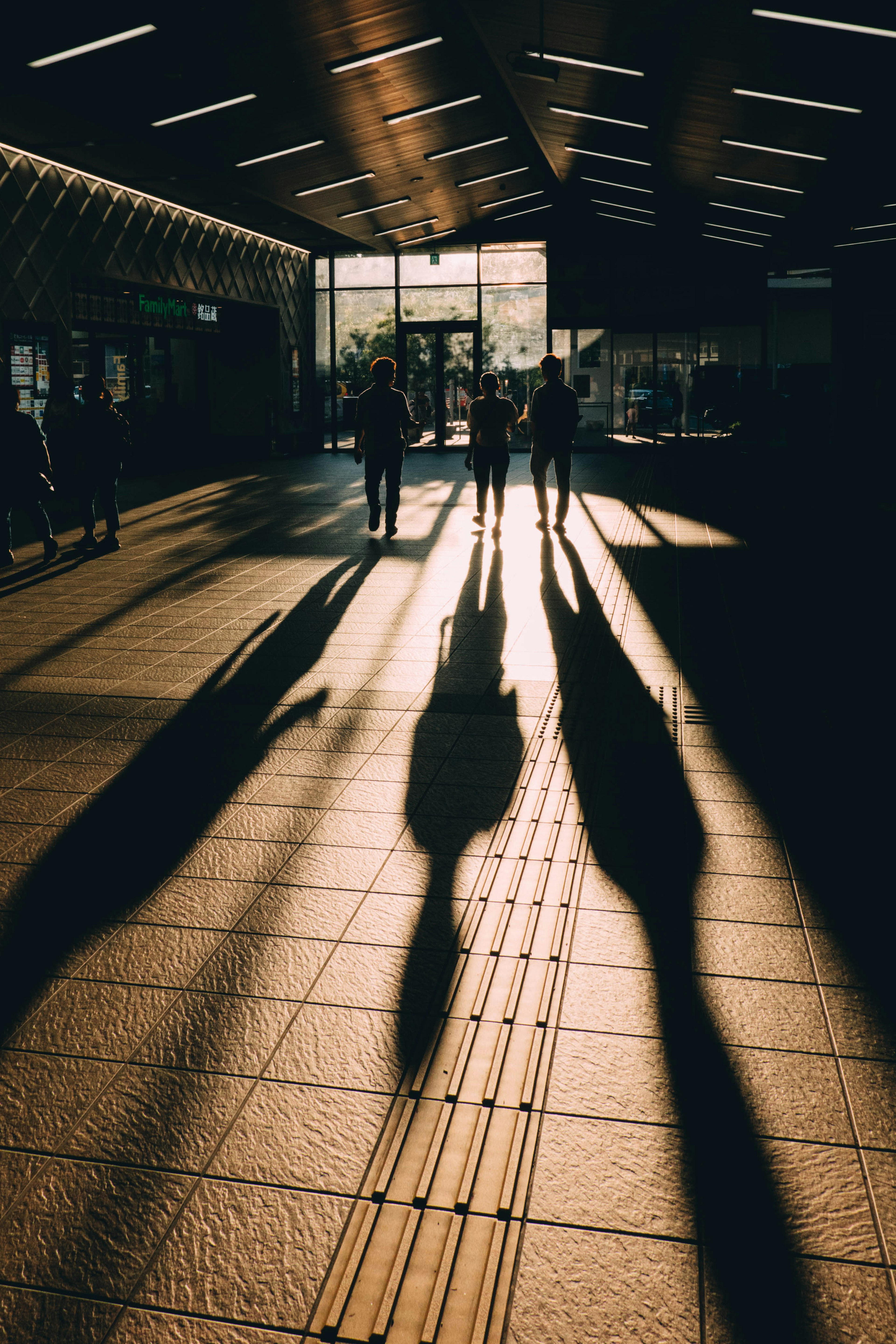 Des gens marchant vers l'entrée d'une station avec de longues ombres