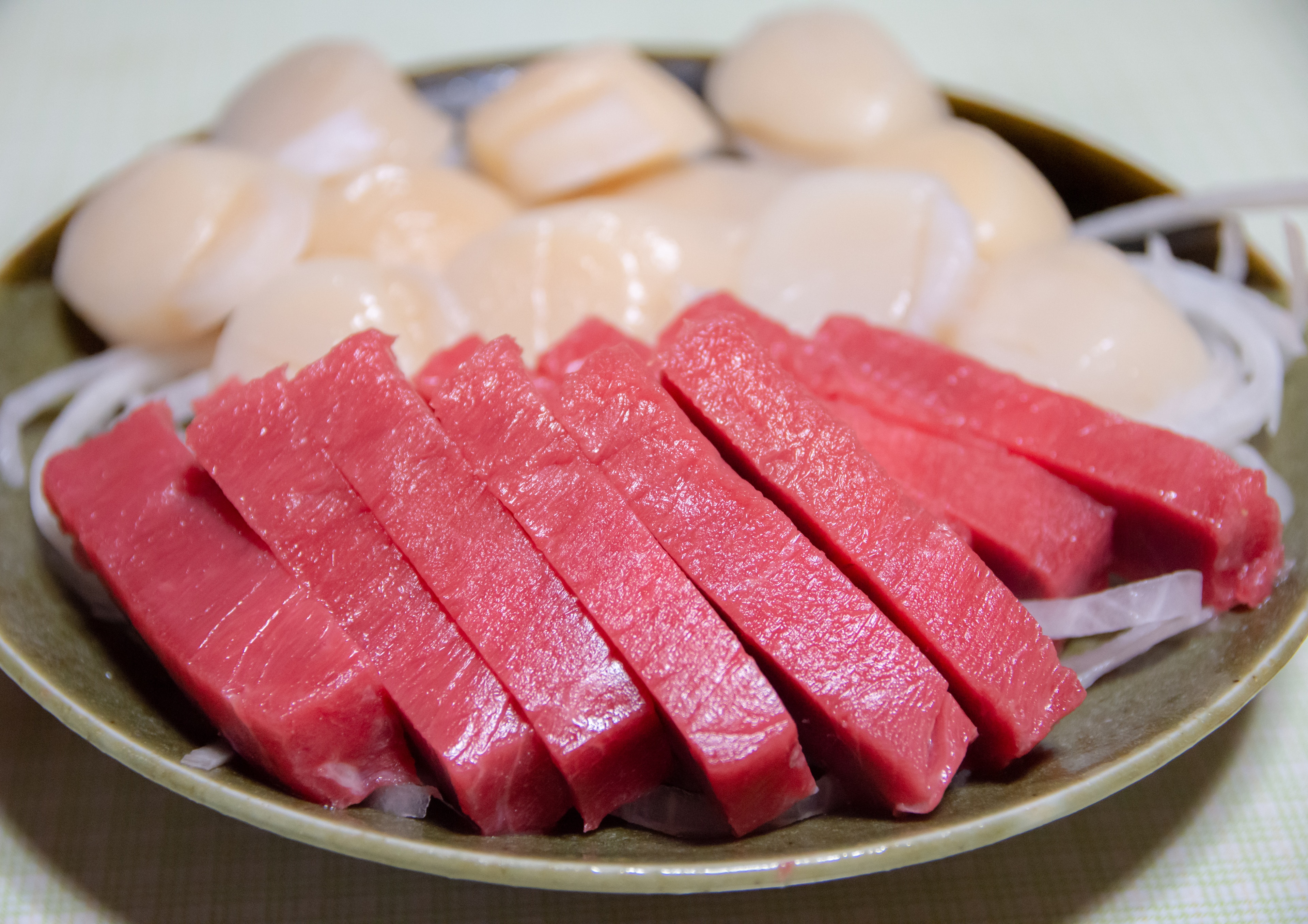 Sliced fresh tuna sashimi and scallops arranged on a plate