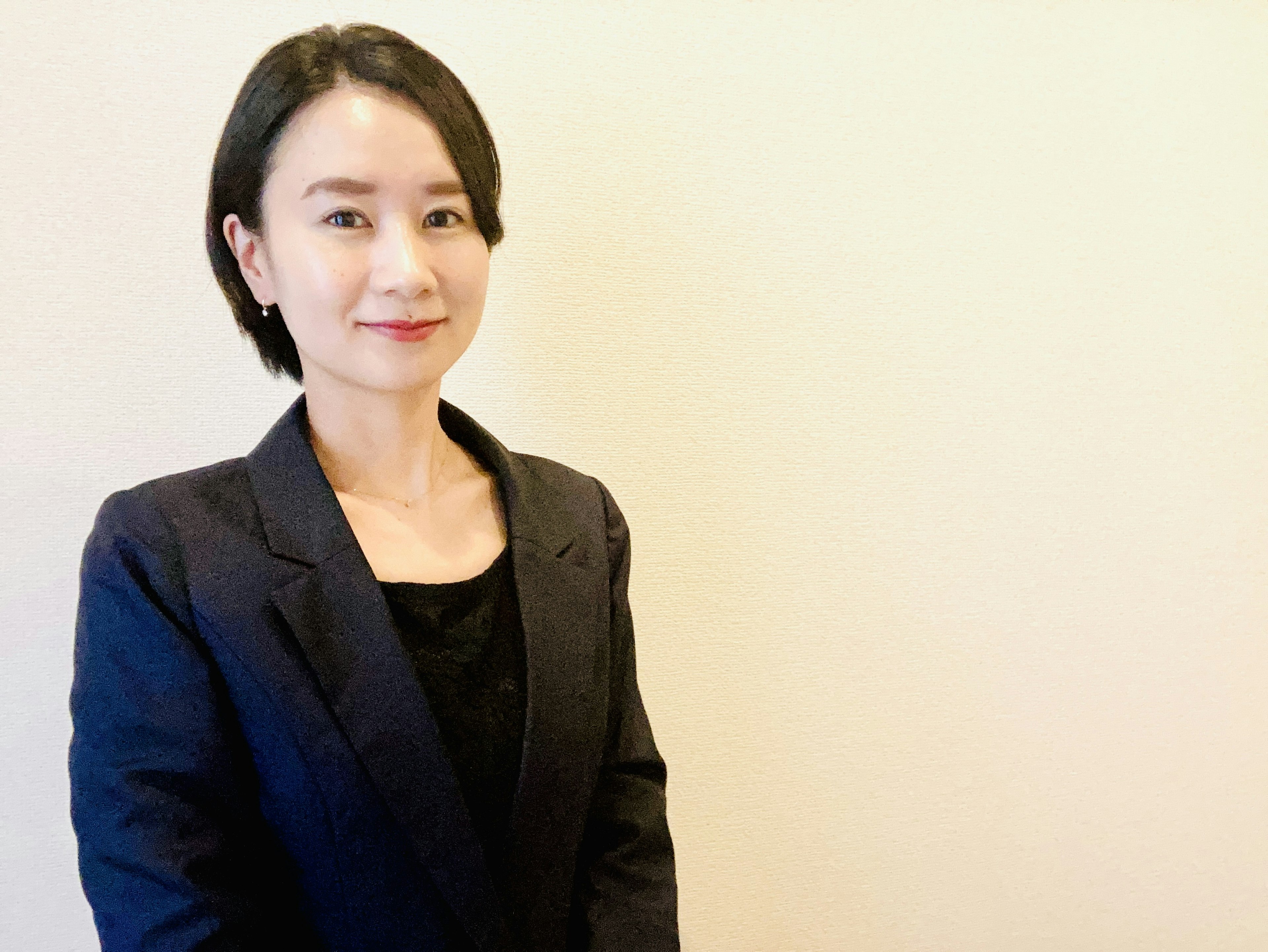 A woman in a business suit smiling against a plain background