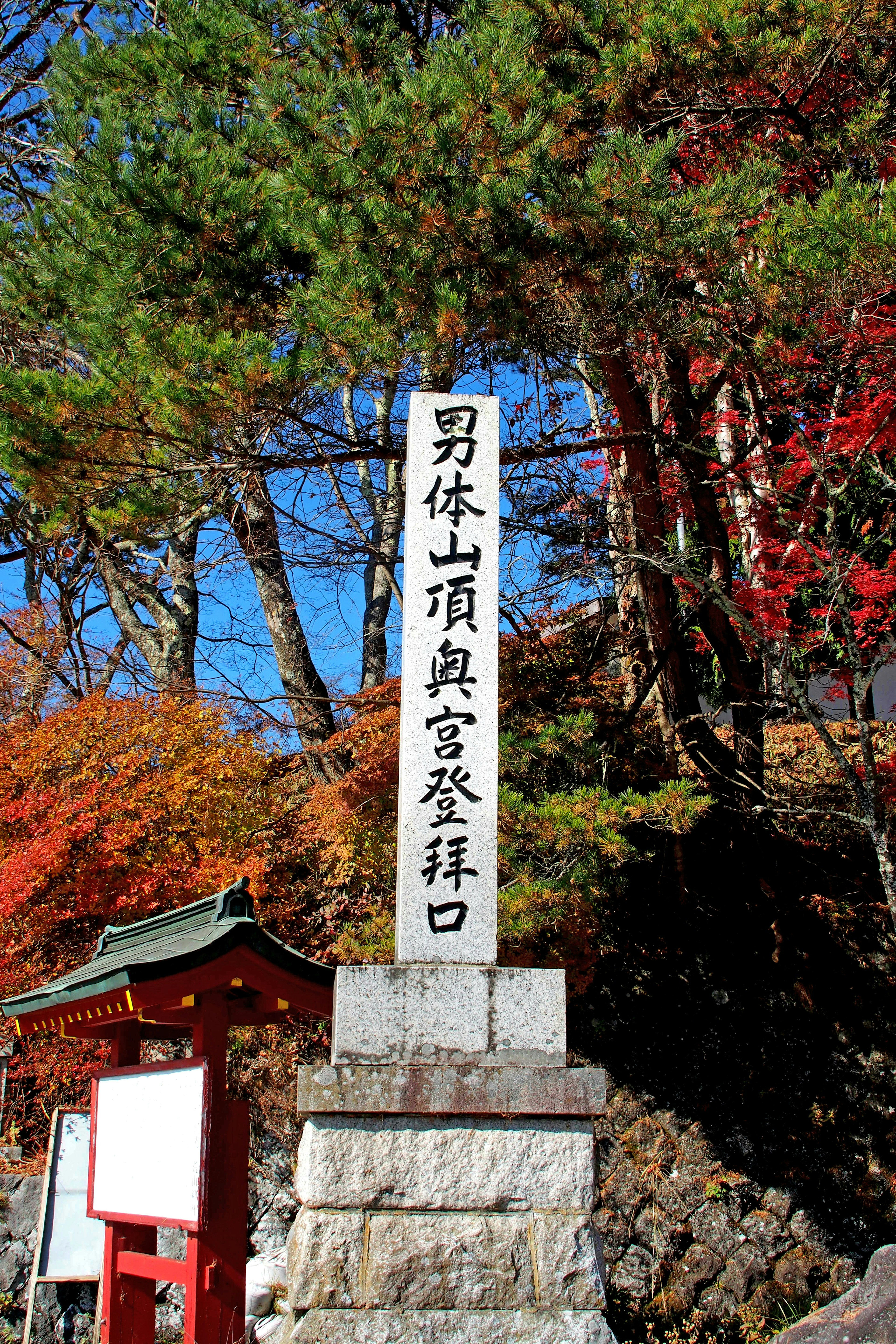 Monumento di pietra che segna l'inizio del sentiero del Monte Nantai con fogliame autunnale