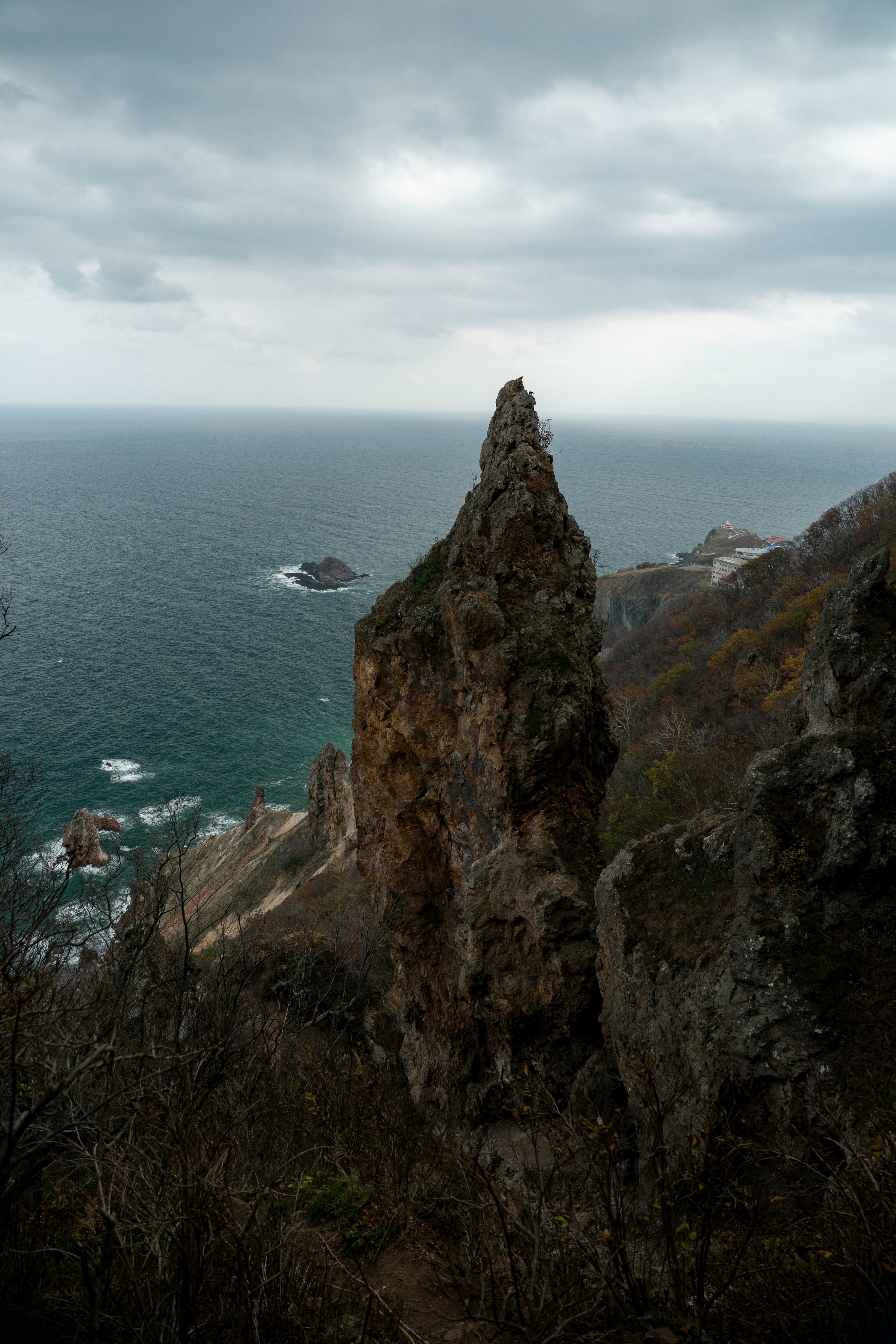 Spitze Felsformation mit Blick auf das Meer und bewölktem Himmel