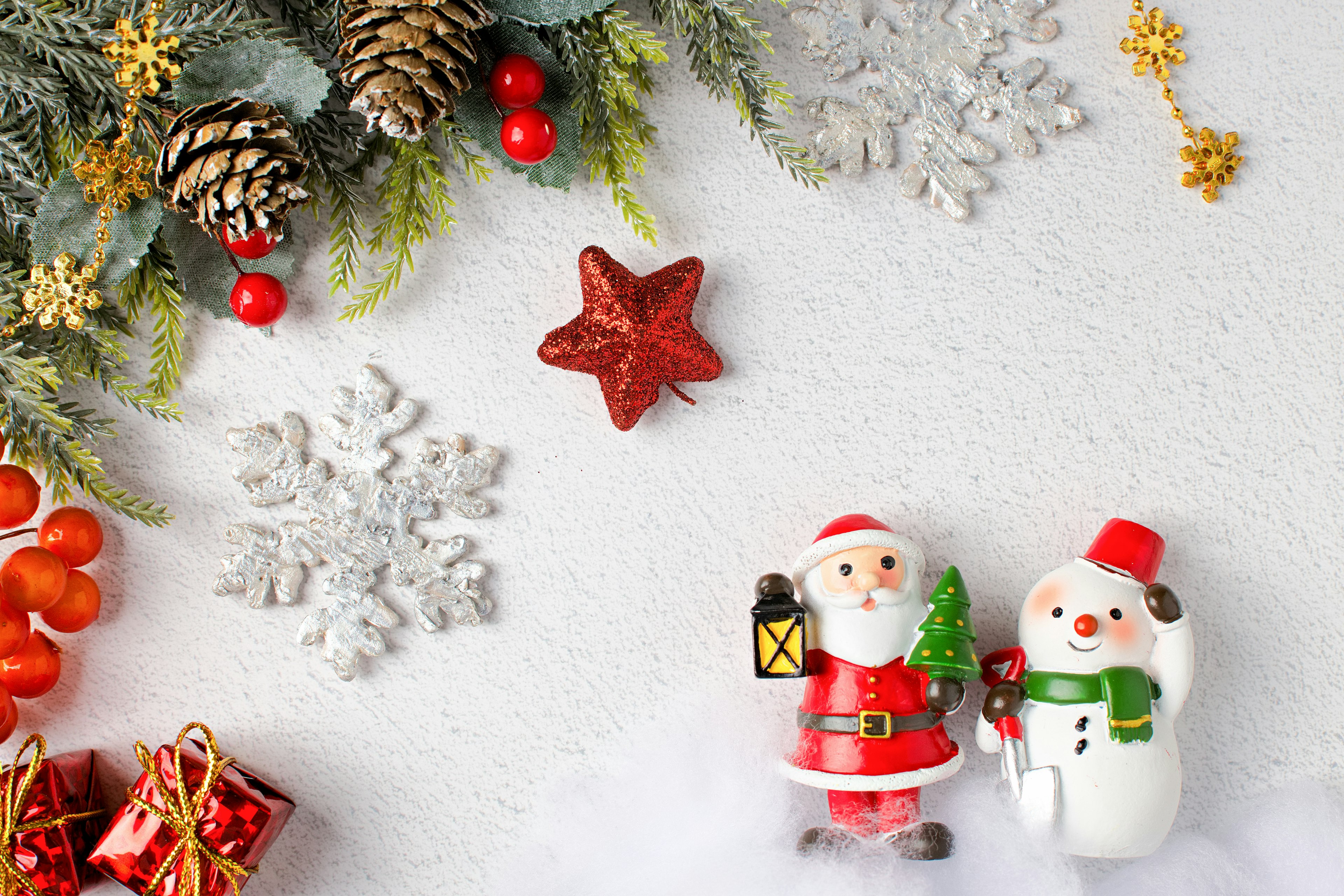 Décorations de Noël avec une figurine de Père Noël et un bonhomme de neige entourés de pommes de pin et de baies rouges