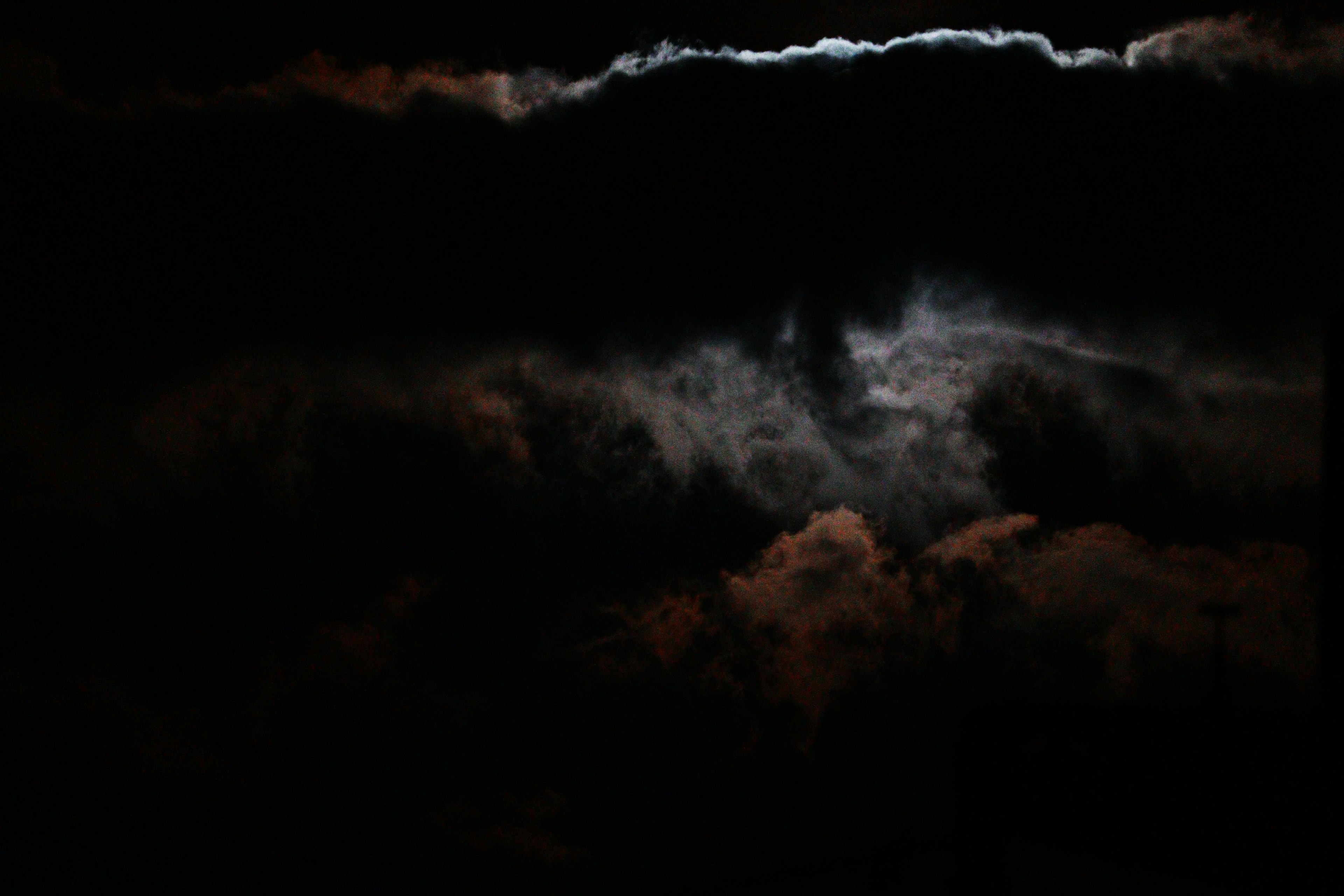 暗い雲に覆われた空に月の光が差し込む様子