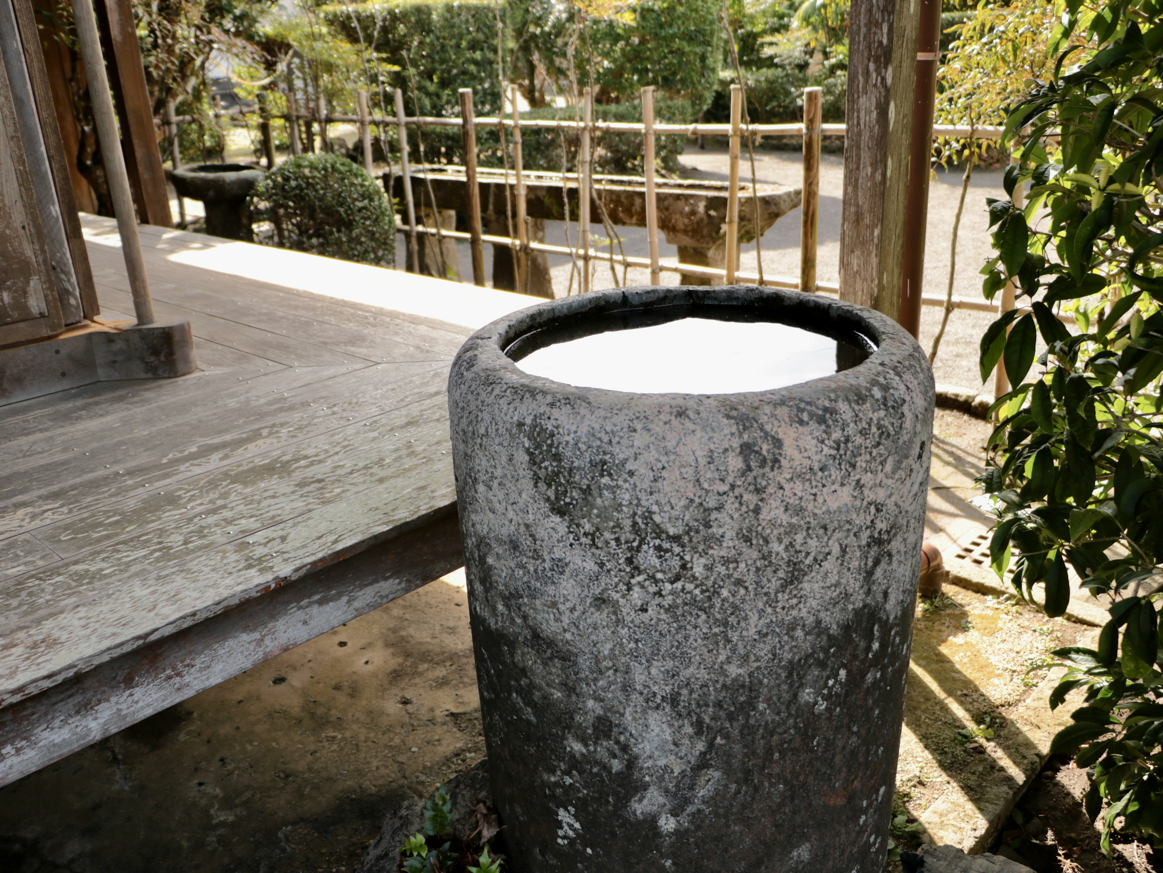 庭にある石の水瓶と周囲の緑の植栽