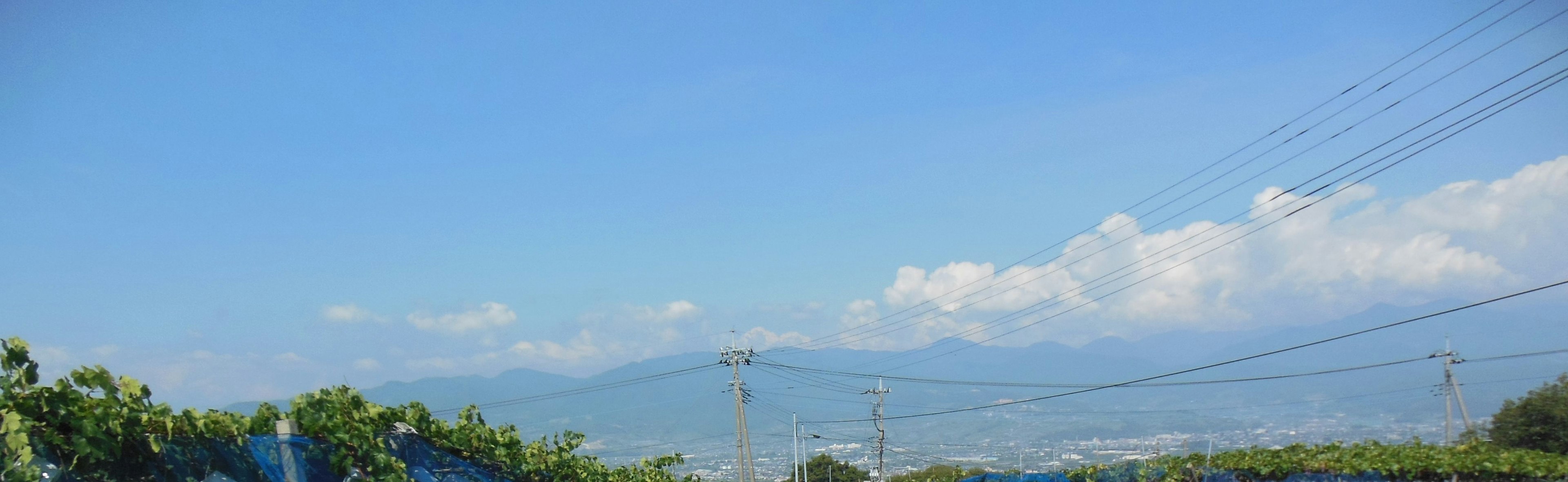 Vista panoramica di montagne sotto un cielo blu con nuvole e linee elettriche