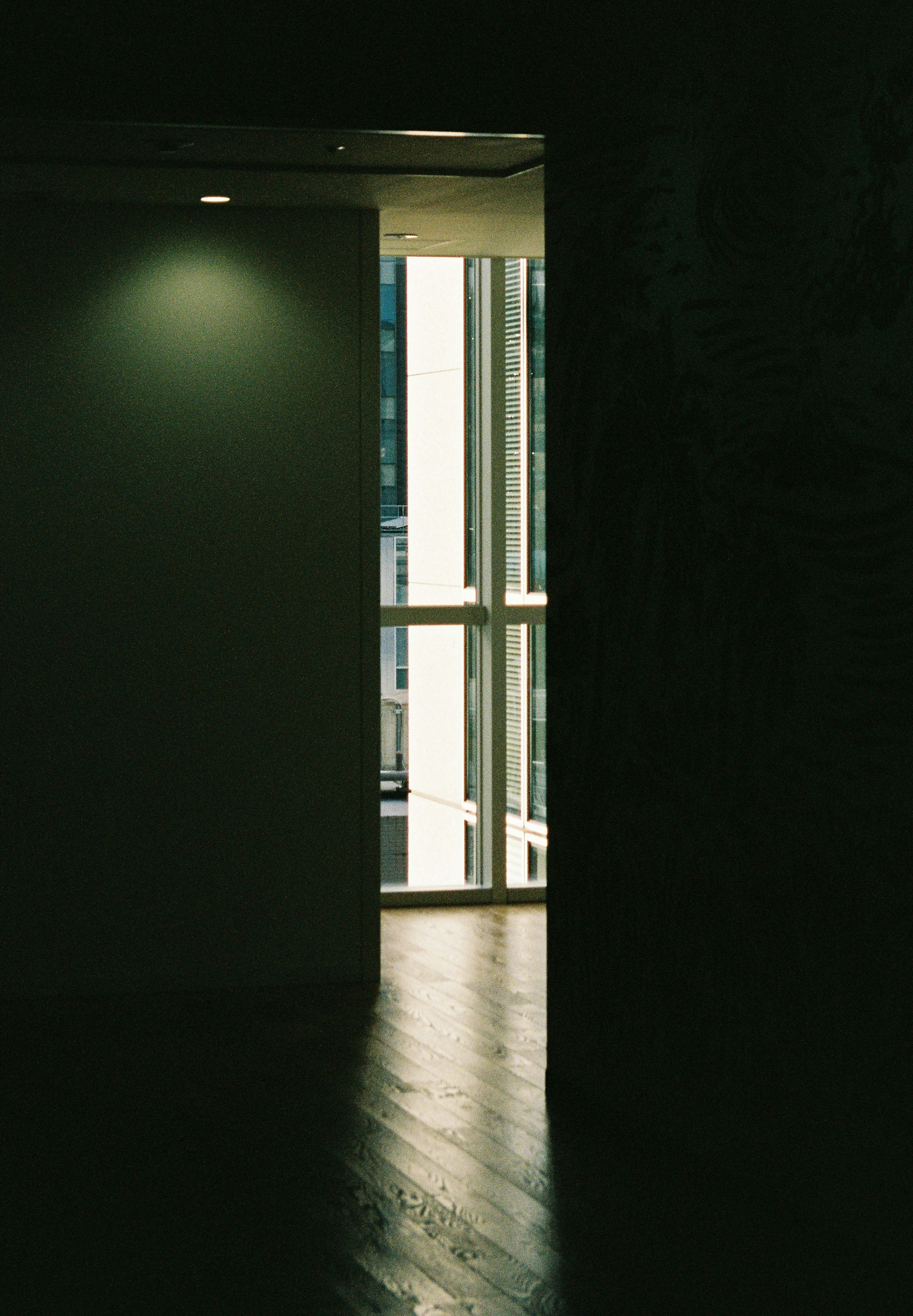 A dark room with a bright window light and wooden floor texture