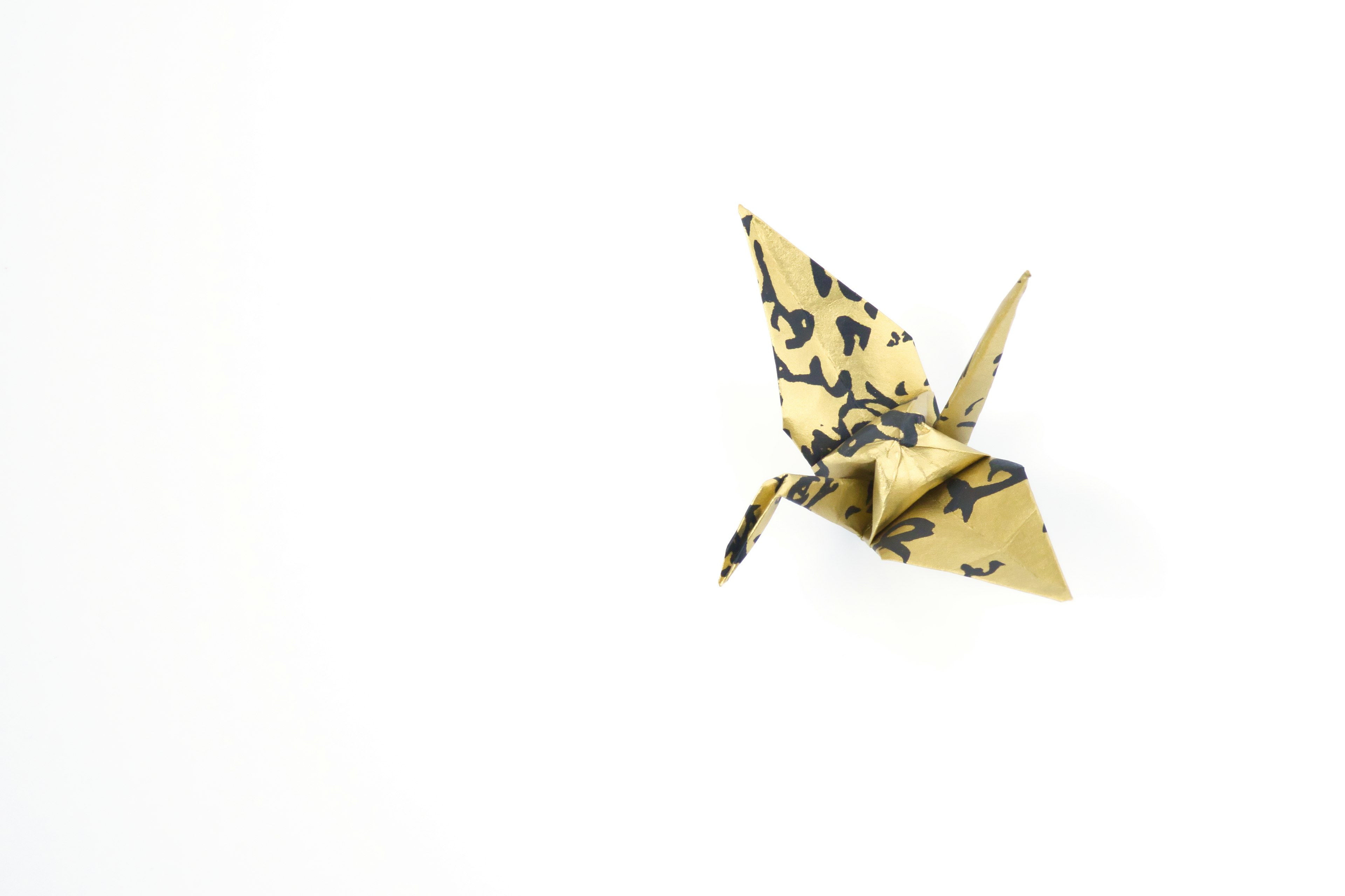 A gold origami crane on a white background