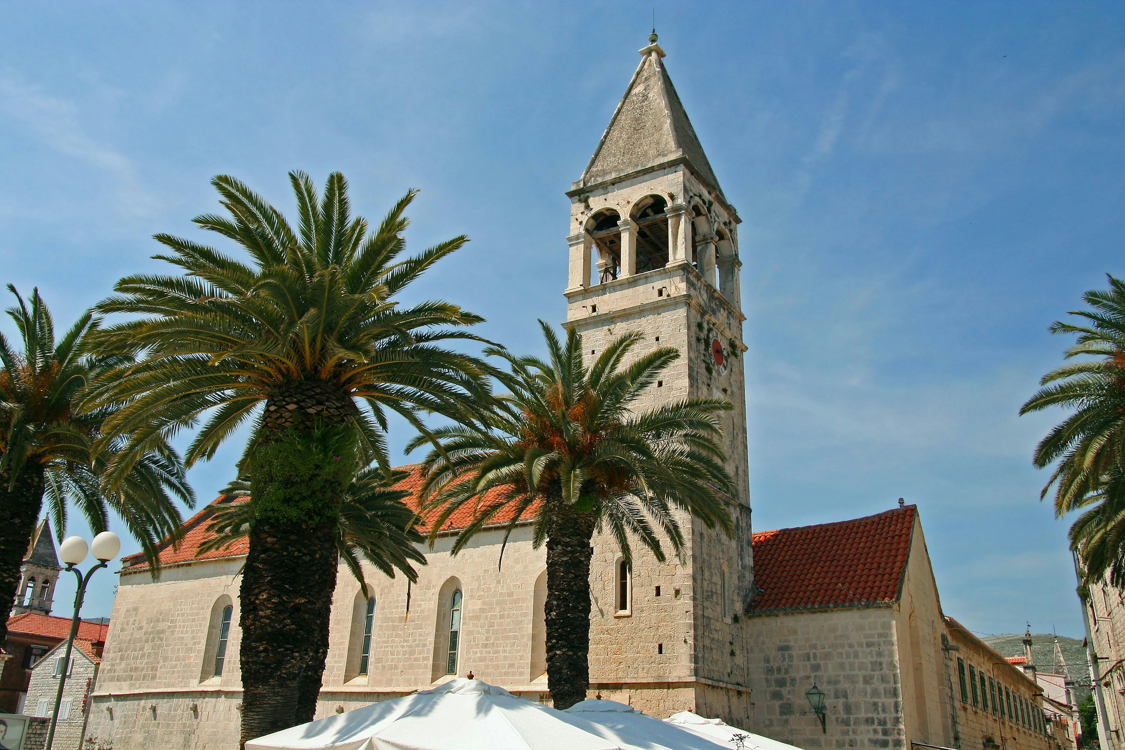 Church tower surrounded by palm trees under a blue sky