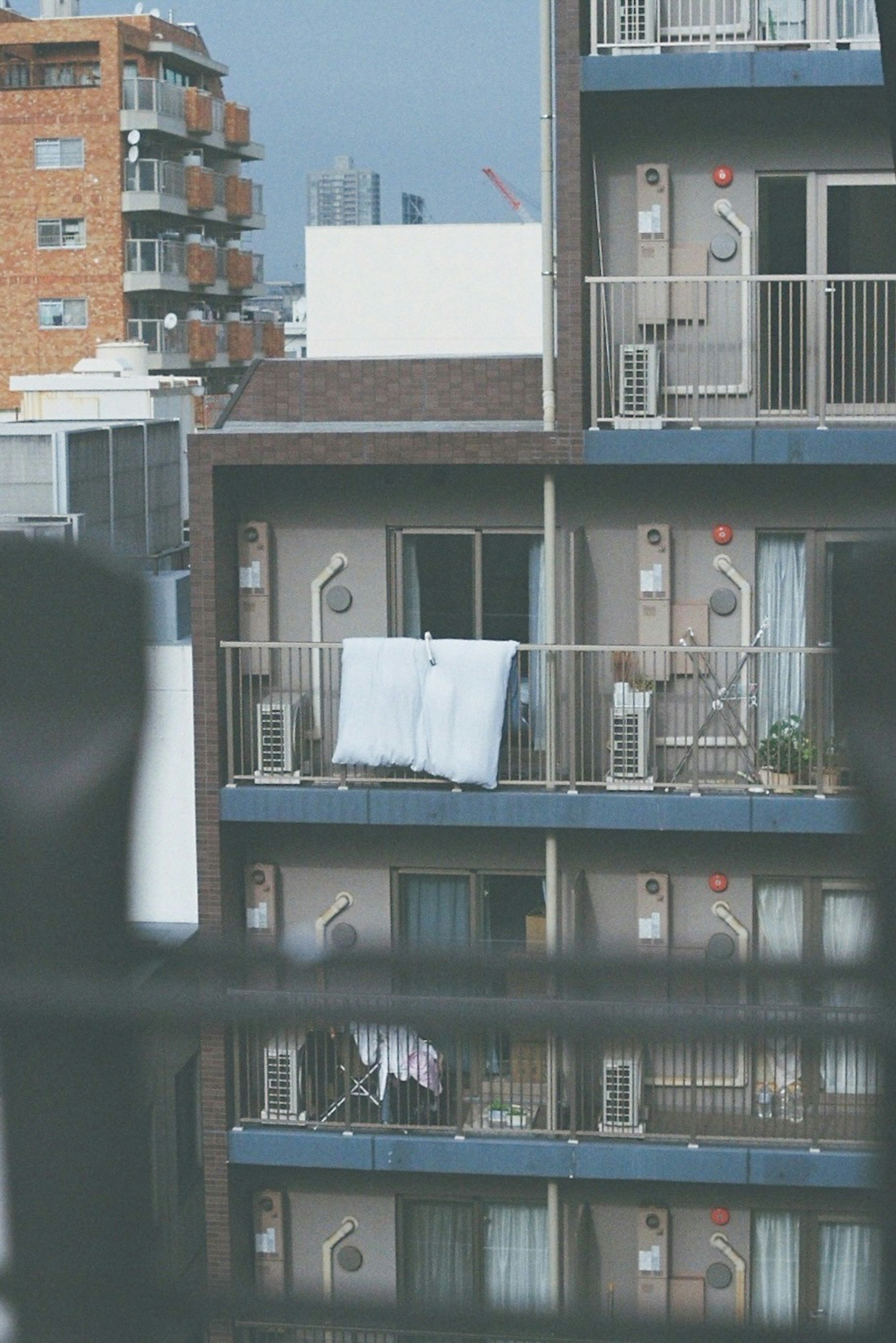 Grauer Balkon mit weißen Bettlaken zum Trocknen und Ausblick auf die umliegenden Wohnungen