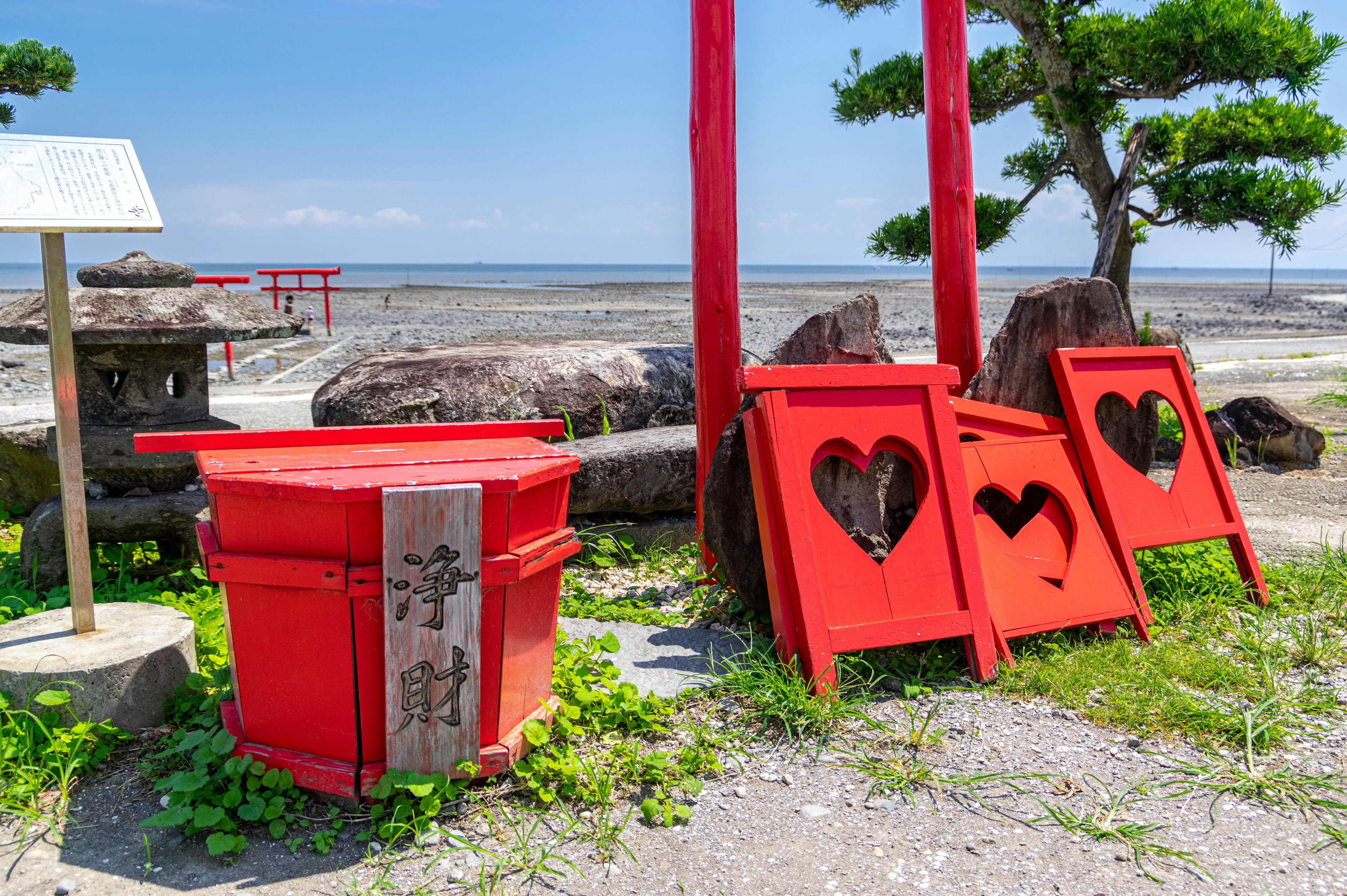 赤い郵便箱とハート型の装飾が施された赤い看板がある海辺の風景