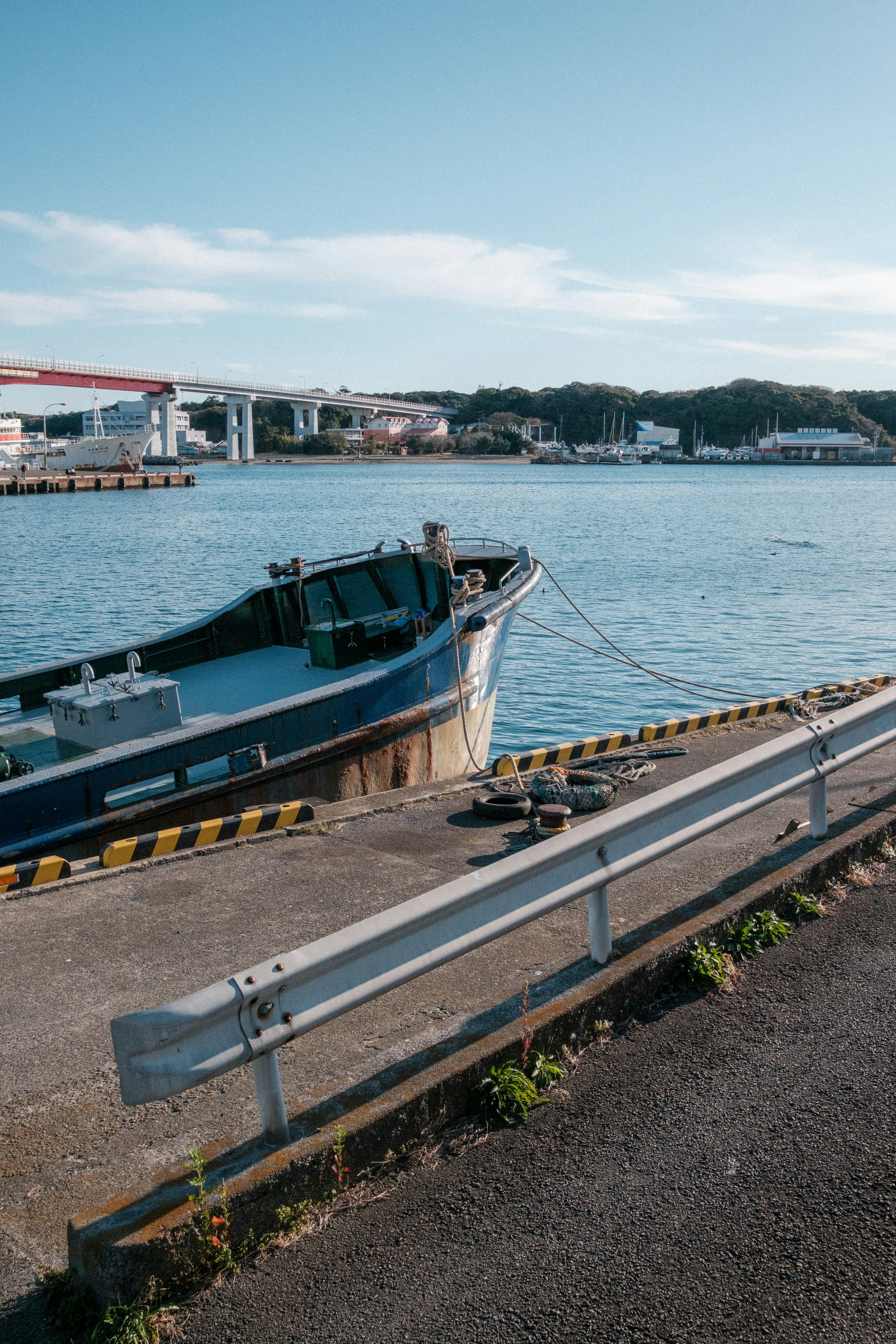 Blue fishing boat docked by the calm water with a scenic background