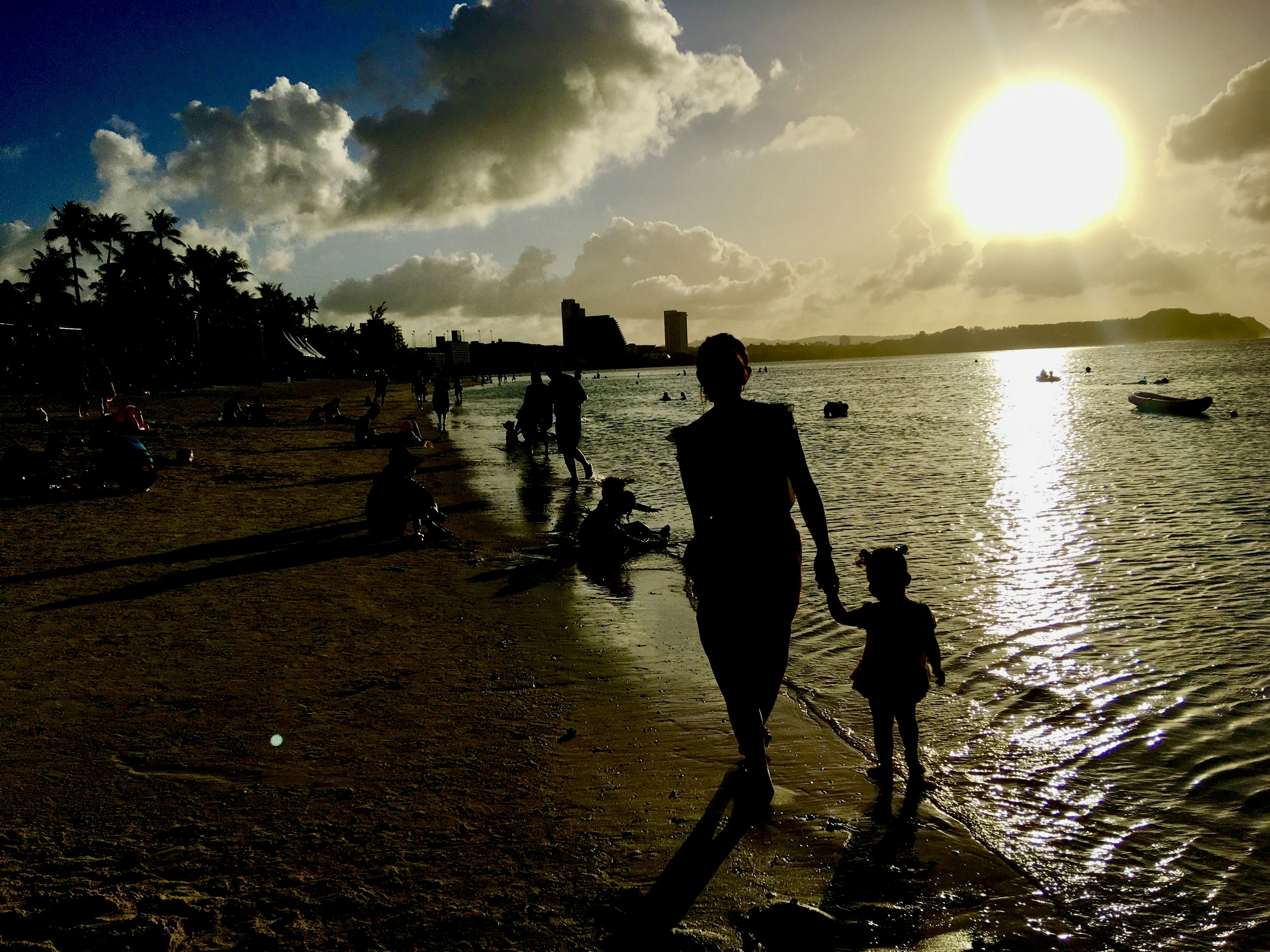 Silhouette of a parent and child walking along the beach at sunset